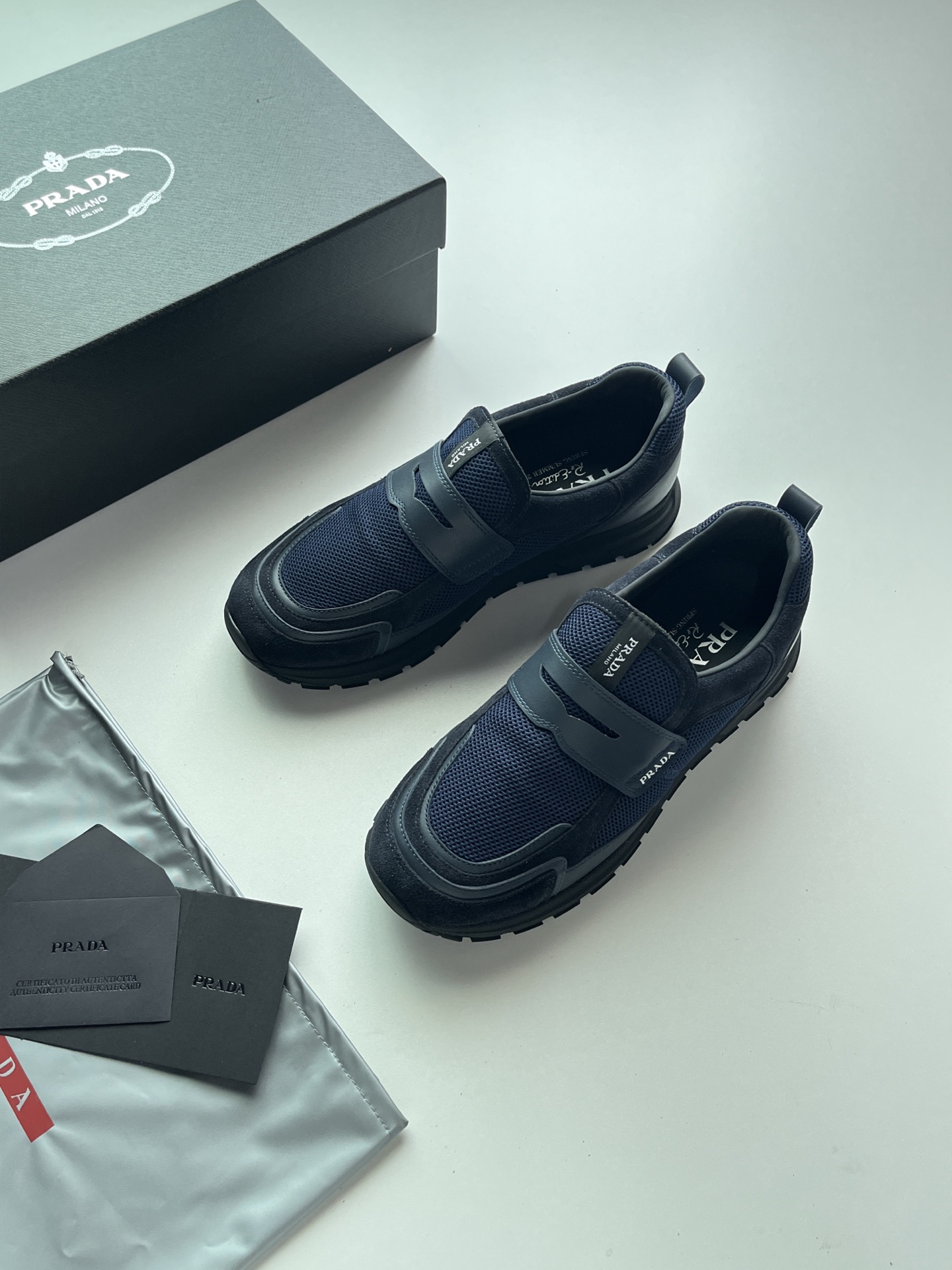 NO:888183,Prax mesh fabric and leather loafers are light luxury casual shoes that combine the formal lines of loafers with the comfortable structure of sports shoes. The main body is breathable mesh fabric with smooth leather trim to replicate the classic loafer strap shape. The woven PRADA logo is sewn on the tongue. The heel is equipped with a pull-up webbing for easy putting on and taking off. Thick toothed rubber sole with a built-in heightening effect of about 4.5cm. Anti-slip and wear-resistant lightweight foam base, taking into account both heightening and walking comfort.  Size 39-45 Color black, white, blue, gray, prada, loafers, sneakers19860909Prax 网眼织物与皮革乐福鞋,轻奢混搭风休闲鞋,融合乐福鞋正装线条与运动鞋舒适结构,主体透气网眼织物,搭配光滑皮革饰条复刻经典乐福横带造型,鞋舌处缝有织唛PRADA标识,后跟配有提拉织带方便穿脱,厚齿纹橡胶厚底,自带约4.5cm增高效果,防滑耐磨轻量化发泡基底,兼顾增高与行走舒适度. 码数39-45 颜色黑色、白色、兰色、灰色,,prada,loafers,sneakers,Men's shoes