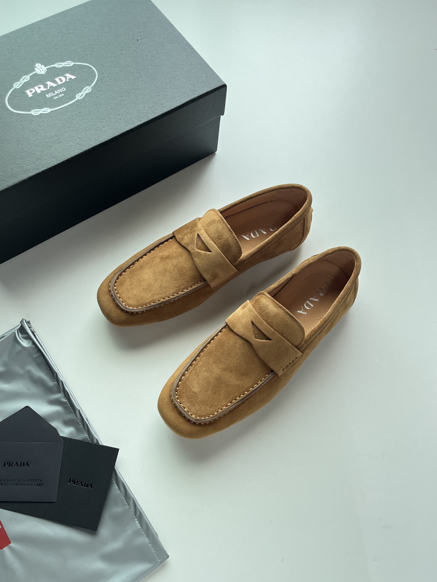 NO:888193,Prada loafers, classic penny Loaf horizontal straps, with the iconic triangular metal logo embedded in the straps, lightweight soft soles, no hard resistance when bending, the edge of the sole is integrated, no unnecessary splicing, waterproof and easy to clean, no laces, one-leg structure, taking into account the formal feel of loafers and the relaxed feel of slippers, the toe is hand-stitched with topstitching to enhance retro workwear details. Size 39-45  Color black leather, gray velvet, apricot velvet, coffee velvet, prada, loafers, slippers19860909Prada豆豆乐福鞋,鞋身经典便士乐福横带,饰带内嵌标志性三角金属徽标,轻量化软底,弯折无硬阻力,鞋底边缘一体成型,无多余拼接,防水易清洁,无鞋带一脚蹬结构,兼顾乐福正式感与拖鞋松弛感,鞋头采用手工箍缩明线车缝,强化复古工装细节. 码数39-45 颜色黑皮、灰绒、杏绒、咖绒,,prada,loafers,slippers,Men's shoes