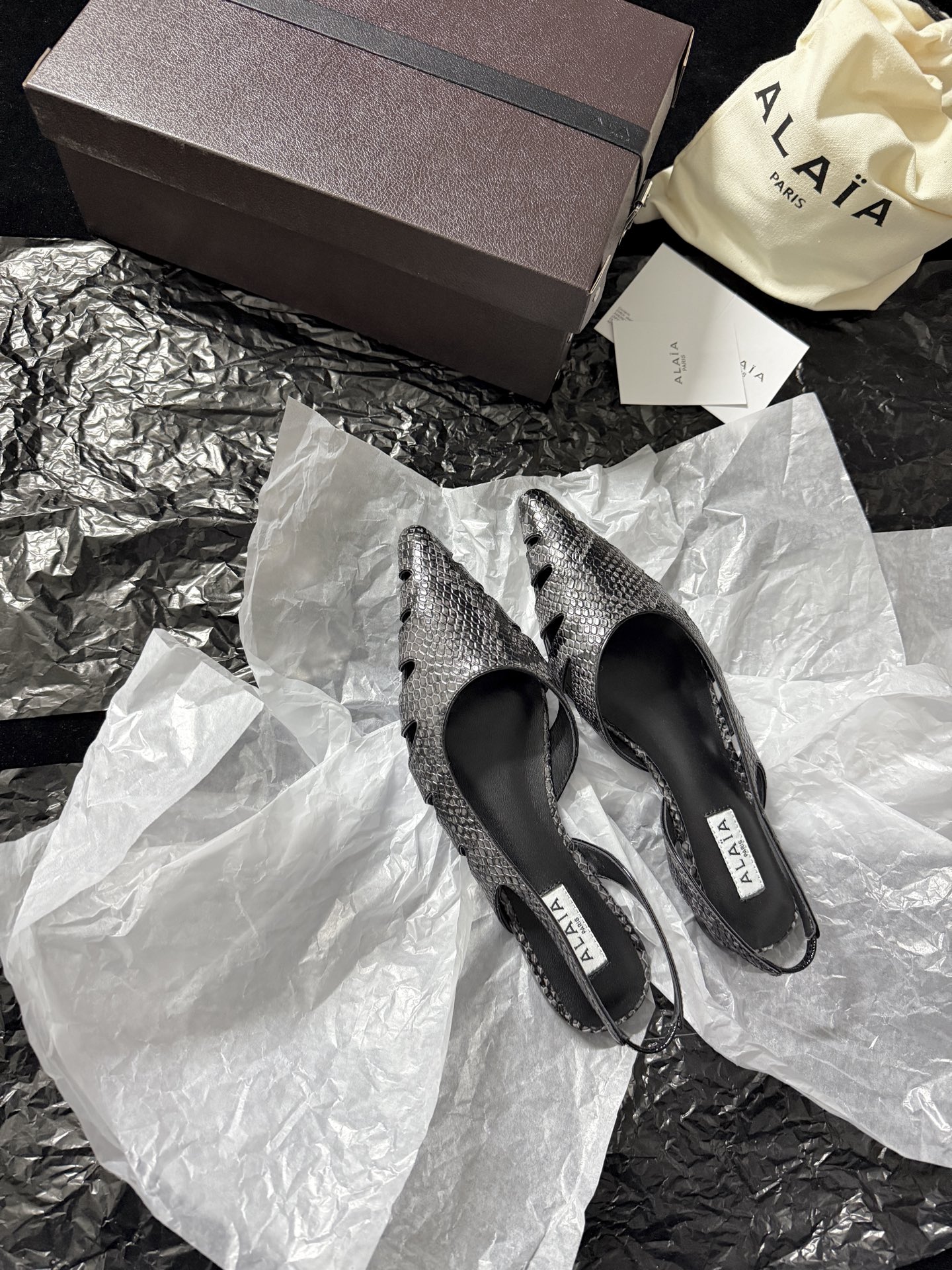 NO:723905,ALAIA / New product ALAA Snake pattern hollow back sandals | The wild flowing poetry of haute couture ALAA reinvents the hollow back sandals with snake-print embossed leather. The geometric hollow cutting wraps around the foot like a sculpture. The pointed toe and back design find the perfect balance between sexy and light. The snake grain texture glows with a cool luster under the light. The hollow design not only eliminates the heavy feeling of leather but also outlines the sexy outline of the foot.  Inject the pioneering gene of haute couture into every detail. Imported cowhide for the upper, imported sheepskin for the lining, and imported genuine leather outsole. Heel height 10cm, 35-39 (set at 40.41.42), high heels and sandals, alaia, sandals, high heels, cowhide, sheepskin, Leather soles.19860909ALAIA /新品 ALAA 蛇纹镂空后空凉鞋｜高定野性的流动诗意 ALAA 以蛇纹压纹皮革重塑后空凉鞋 几何镂空切割如雕塑般缠绕足间 尖头与后空设计在性感与轻盈间找到完美平衡 蛇纹肌理在光线下泛着冷冽光泽 镂空设计既消解了皮革的厚重感 又勾勒出足部的性感轮廓 将高定的先锋基因注入每一处细节 鞋面进口牛皮 内里进口羊皮 进口真皮大底 跟高10cm 35-39（40.41.42定）,高跟鞋凉鞋,alaia,sandals,high heels,cowhide,sheepskin,Leather soles,Women's Shoes