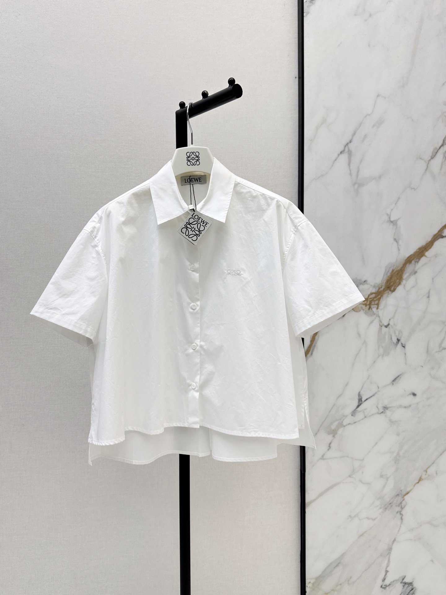 NO:908277,Loe 26Ss - the latest short-sleeved shirt for early autumn. It is made of high-quality cotton fabric. It is super comfortable to wear in summer. Classic lapel + front buttons. Simple and generous. Loose fit. Short front and long back design. Not picky about body shape. The hem is full of small brand embroidery details. It can be easily worn in daily casual or party. Pair it with light-colored bottoms or jeans. It is easy to get a vibrant summer look. Two-color smlxl,,loewe,jeans,shirts,T-shirt,19860909Loe 26Ss———早秋最新款短款短袖衬衫 采用高品质棉面料 夏天穿超舒服 经典翻领+正面纽扣 简约又大方 宽松版型 前短后长设计 不挑身材 下摆品牌小刺绣细节感满满 日常休闲 聚会都能轻松驾驭 搭配浅色下装或牛仔裤 轻松get活力夏日look 两色smlxl,,loewe,jeans,shirts,T-shirt,,Women's clothing