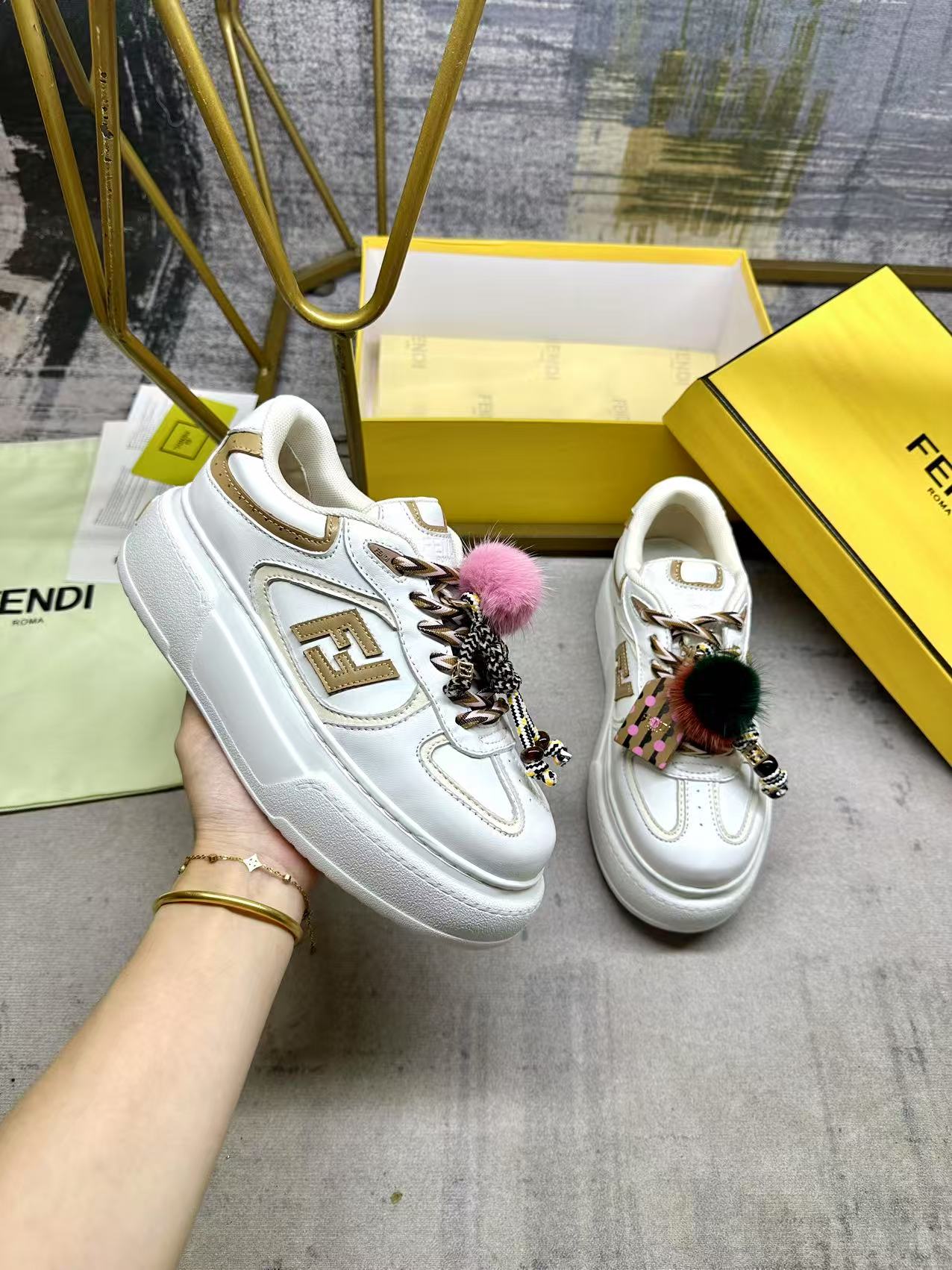 NO:592478,FENDI  Match lace-up sneakers. White fabric with beige details. Contrast leather FF appliqués on the sides and hiking laces in white, beige and brown. Thick rubber sole with oversized raised embossed FENDI lettering at the heel. Metal ring charm on the tongue. Contrast mink detailing and gold metallic F on the right shoe.  Small braided doll with F pattern bracelet. The left shoe is decorated with a braided rope with contrasting mink double pom-poms, decorated with metal FF beads and Pequin print pattern and logo (the doll is removable), sizes 35-42, casual shoes/sneakers, fendi, sneakers, bracelet19860909FENDI Match系带运动鞋.白色面料,带米色细节.侧边饰有撞色皮革FF贴花,白色、米色和棕色登山鞋带.橡胶厚鞋底,后跟处饰有超大凸纹压花FENDI字样.鞋舌上饰有金属环挂饰右鞋上饰有带撞色貂毛细节和金色金属FF图案手链的编绳小玩偶.左鞋上饰有一条带撞色貂毛双绒球的编绳,饰有金属FF圆珠以及Pequin印花图案和标志（玩偶可拆卸）,35-42码,,休闲鞋/运动鞋,fendi,sneakers,bracelet,Women's Shoes