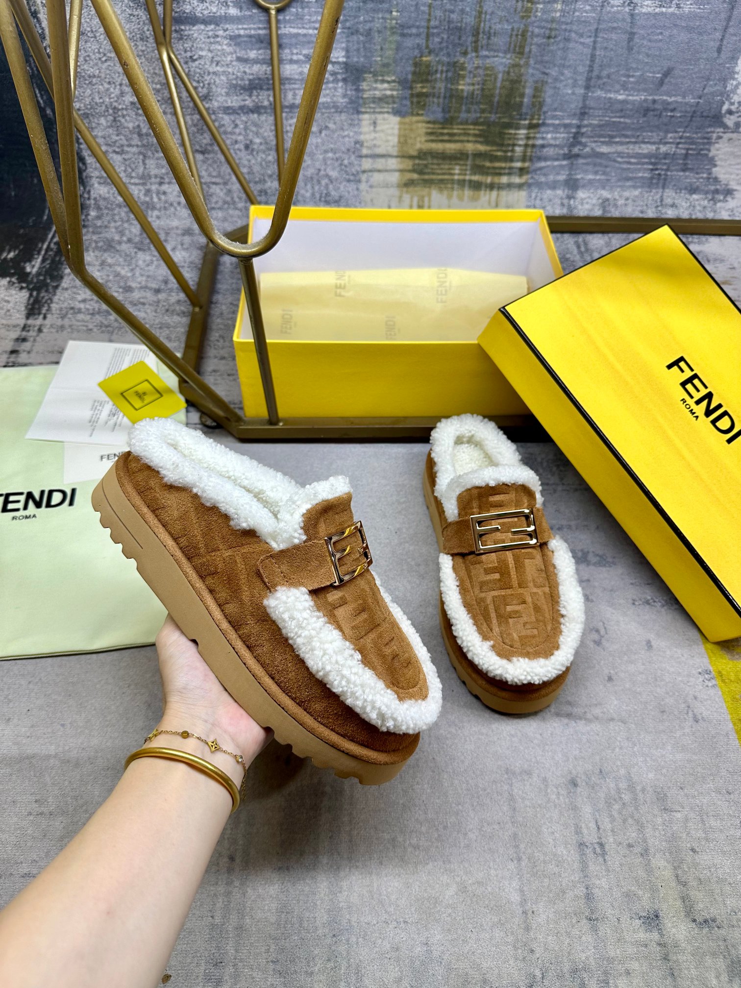 NO:613306,FENDI's latest casual round toe flat semi-slippers. Made of brown suede material decorated with tonal embossed FF pattern. White shearling lining and trim. Decorated with gold-finish metal Baguette accessories. Thick brown non-slip sole, contrasting inlay and FENDI lettering on the heel. Women's size 35-40, men's size 39-45, half-slippers, fendi, slippers19860909FENDI最新休闲圆头平底半拖鞋.采用棕色绒面材质饰有同色系凸纹FF图案.白色羊卷毛内衬和饰边.饰有金色饰面金属Baguette配饰.厚实的棕色防滑底,鞋跟饰有撞色嵌饰和FENDI字样.女35-40码,男39-45码,半拖毛毛鞋,fendi,slippers,Women's Shoes