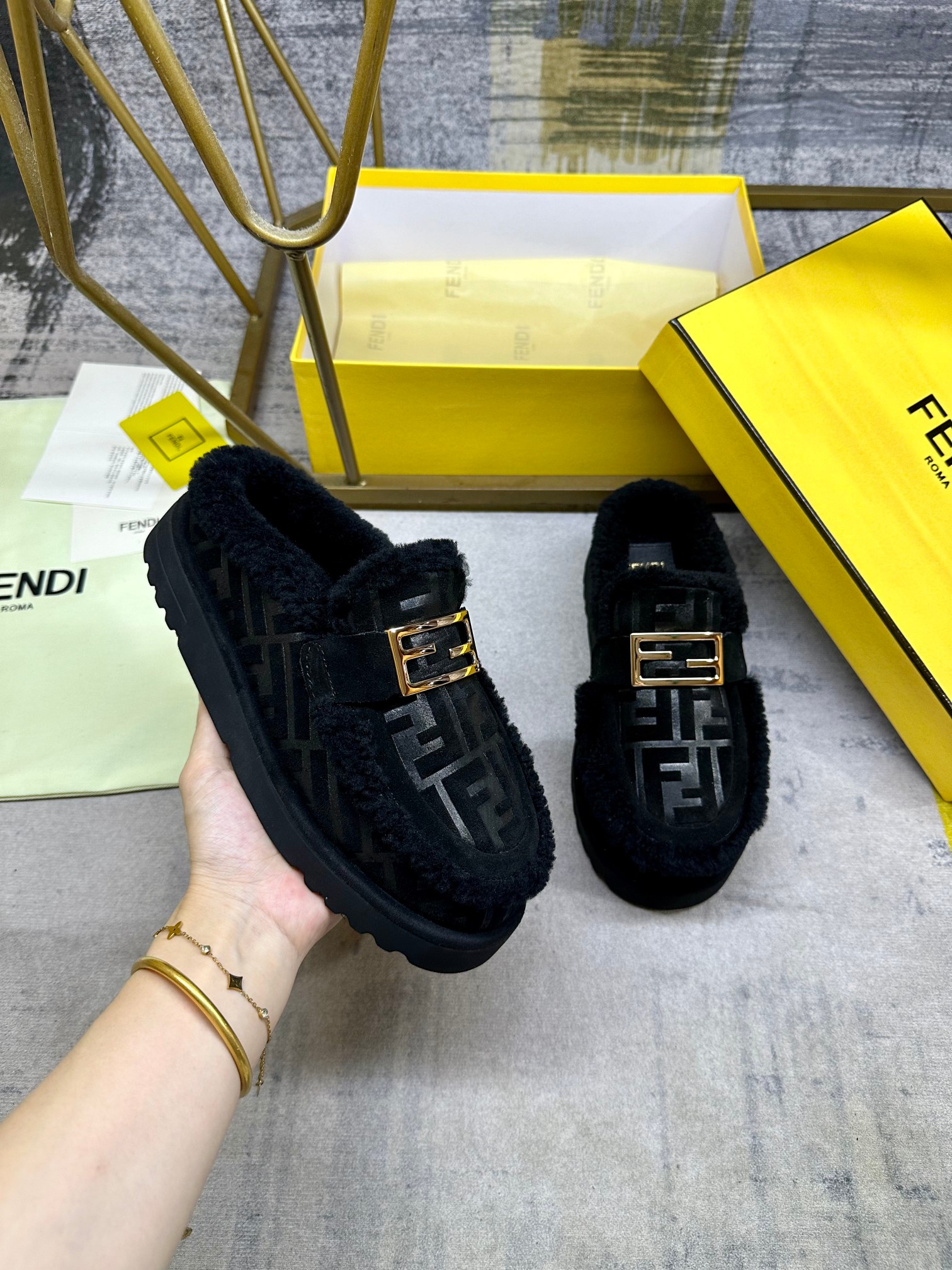 NO:613310,FENDI's latest casual round-toe flat semi-slippers. Made of black suede material with tonal embossed FF pattern. Tonal shearling lining and trim. Decorated with gold-finish metal Baguette accessories. Thick black non-slip sole, contrasting inlay and FENDI lettering on the heel. Women's sizes 35-40, men's sizes 39-45, half-slippers, fendi, slippers19860909FENDI最新休闲圆头平底半拖鞋.采用黑色绒面材质饰有同色系凸纹FF图案.同色羊卷毛内衬和饰边.饰有金色饰面金属Baguette配饰.厚实的黑色防滑底,鞋跟饰有撞色嵌饰和FENDI字样.女35-40码,男39-45码,半拖毛毛鞋,fendi,slippers,Women's Shoes