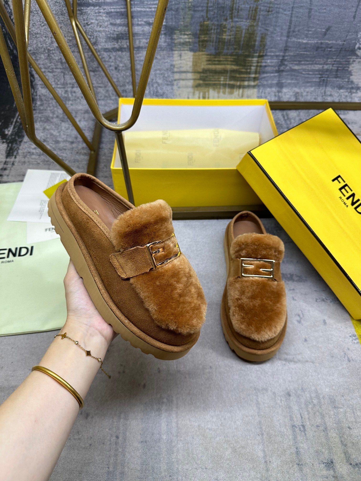 NO:613299,FENDI's latest après-ski casual round-toe flats. Brown suede material, with straight fur tongue of the same color. Decorated with gold-finished metal Baguette accessories. Thick brown non-slip sole, FENDI lettering on the heel, women's size 35-40, men's size 39-45, half-slip fur shoes, fendi, flats19860909FENDI最新滑雪后休闲圆头平底鞋.棕色绒面材质,配有同色系直毛鞋舌.饰有金色饰面金属Baguette配饰.厚实的棕色防滑鞋底,鞋跟饰有FENDI字样,女35-40码,男39-45码,半拖毛毛鞋,fendi,flats,Women's Shoes