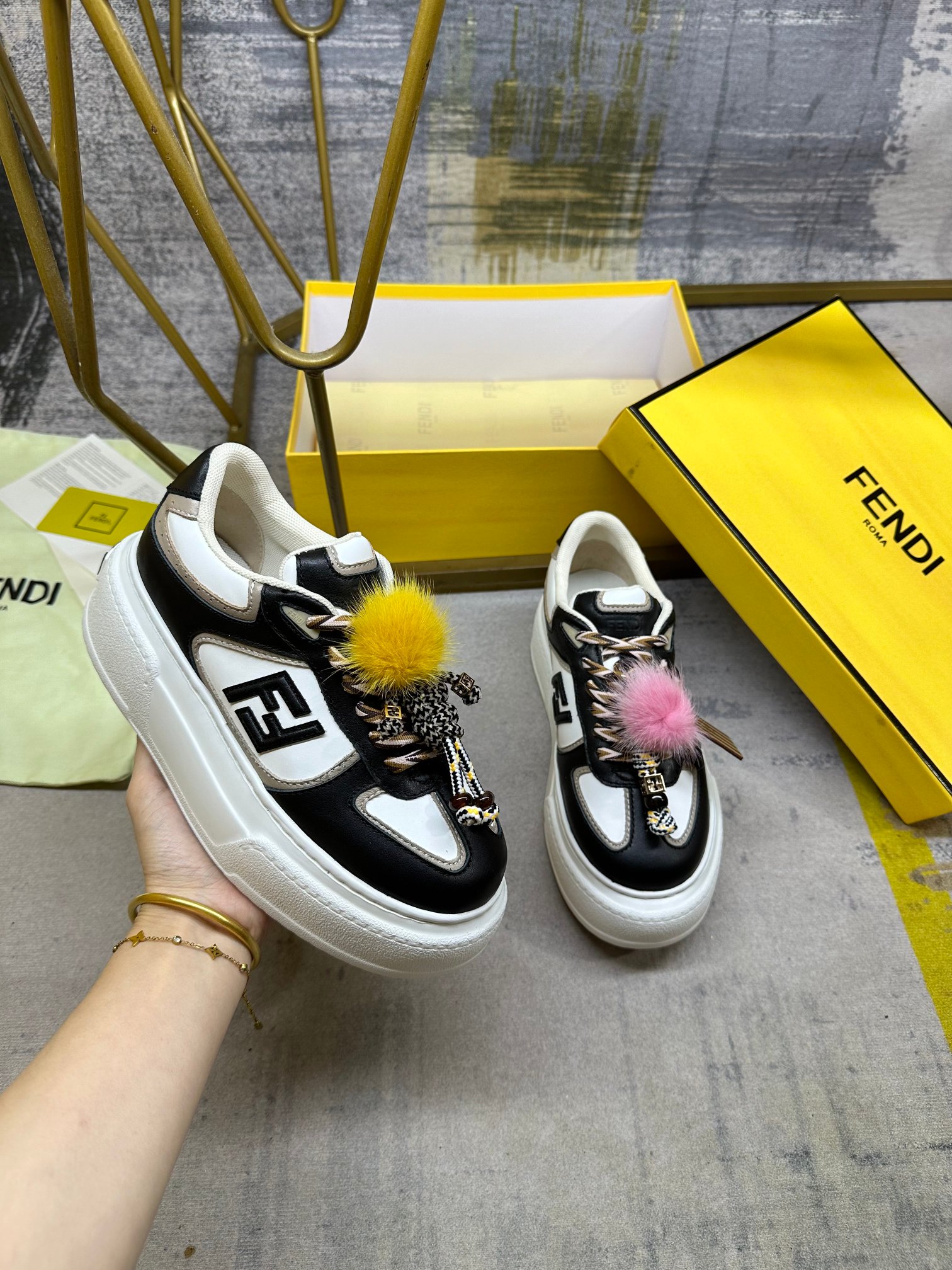 NO:592486,FENDI  Match lace-up sneakers. Black and white leather with black leather FF appliqués on the sides, color-blocked laces. Thick rubber sole with oversized raised FENDI lettering on the heel. Metal ring charm on the tongue Braided cord with yellow mink details and gold metal FF pattern bracelet on the right shoe  Small doll. The left shoe is decorated with a braided rope with contrasting mink double pom poms, metal FF beads, and Pequin print pattern and logo (the doll is removable), size 35-42, casual shoes/sneakers, fendi, sneakers, bracelet19860909FENDI Match系带运动鞋.黑白色皮料侧面饰有黑色皮革FF贴花,拼色鞋带.橡胶厚鞋底,后跟处饰有超大凸纹FENDI字样.鞋舌上饰有金属环挂饰右鞋上饰有带黄色貂皮细节和金色金属FF图案手链的编绳小玩偶.左鞋上饰有一条带撞色貂毛双绒球的编绳,饰有金属FF圆珠,以及Pequin印花图案和标志（玩偶可拆卸）,35-42码,,休闲鞋/运动鞋,fendi,sneakers,bracelet,Women's Shoes