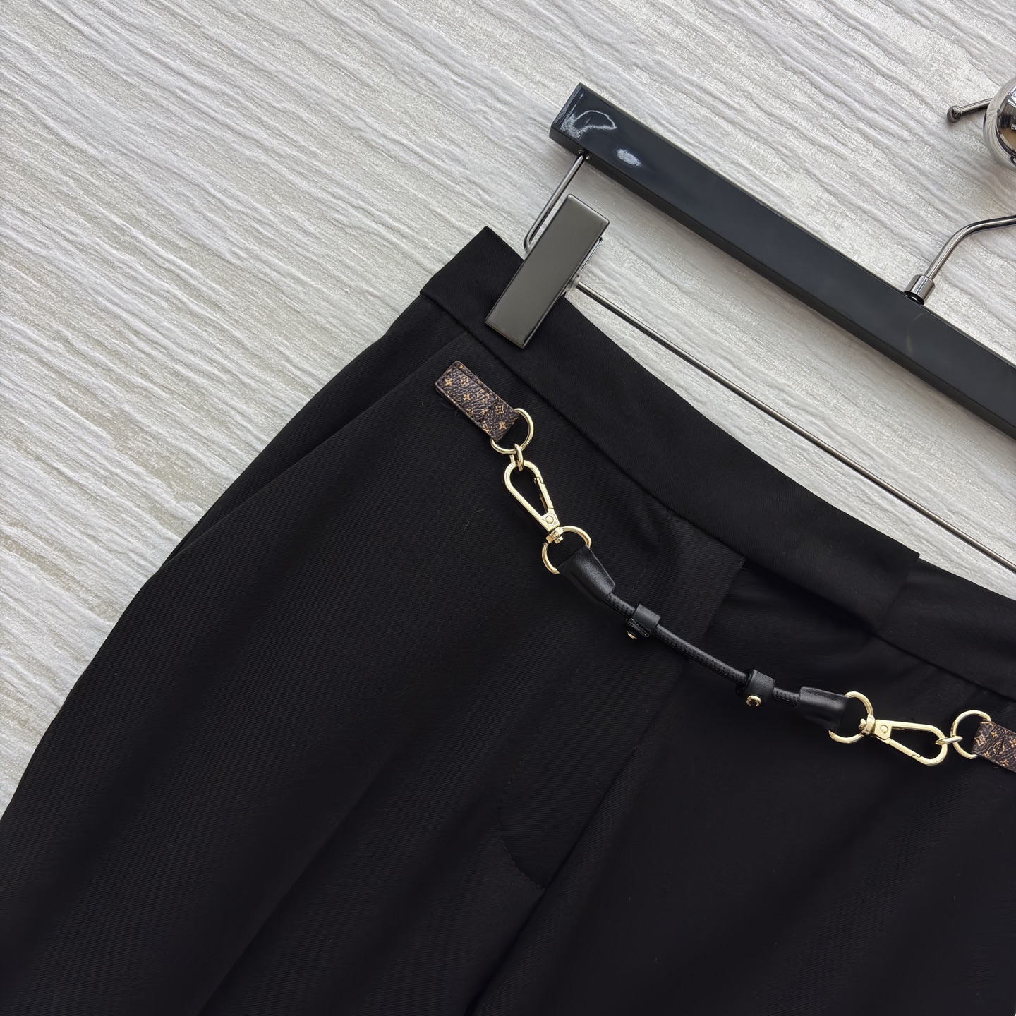 L家 皮扣设计黑色微喇西裤 腰间金属链条装饰瞬间打破单调 为职场穿搭注入个性巧思 利落版型修饰腿型 无论