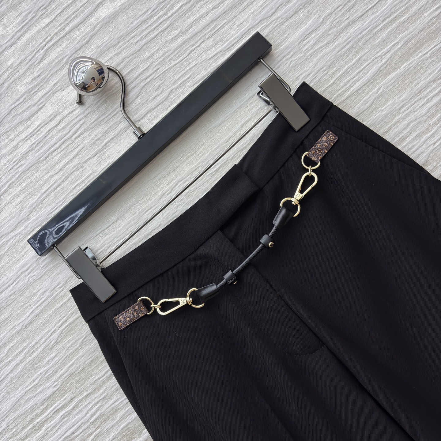 L家 皮扣设计黑色微喇西裤 腰间金属链条装饰瞬间打破单调 为职场穿搭注入个性巧思 利落版型修饰腿型 无论