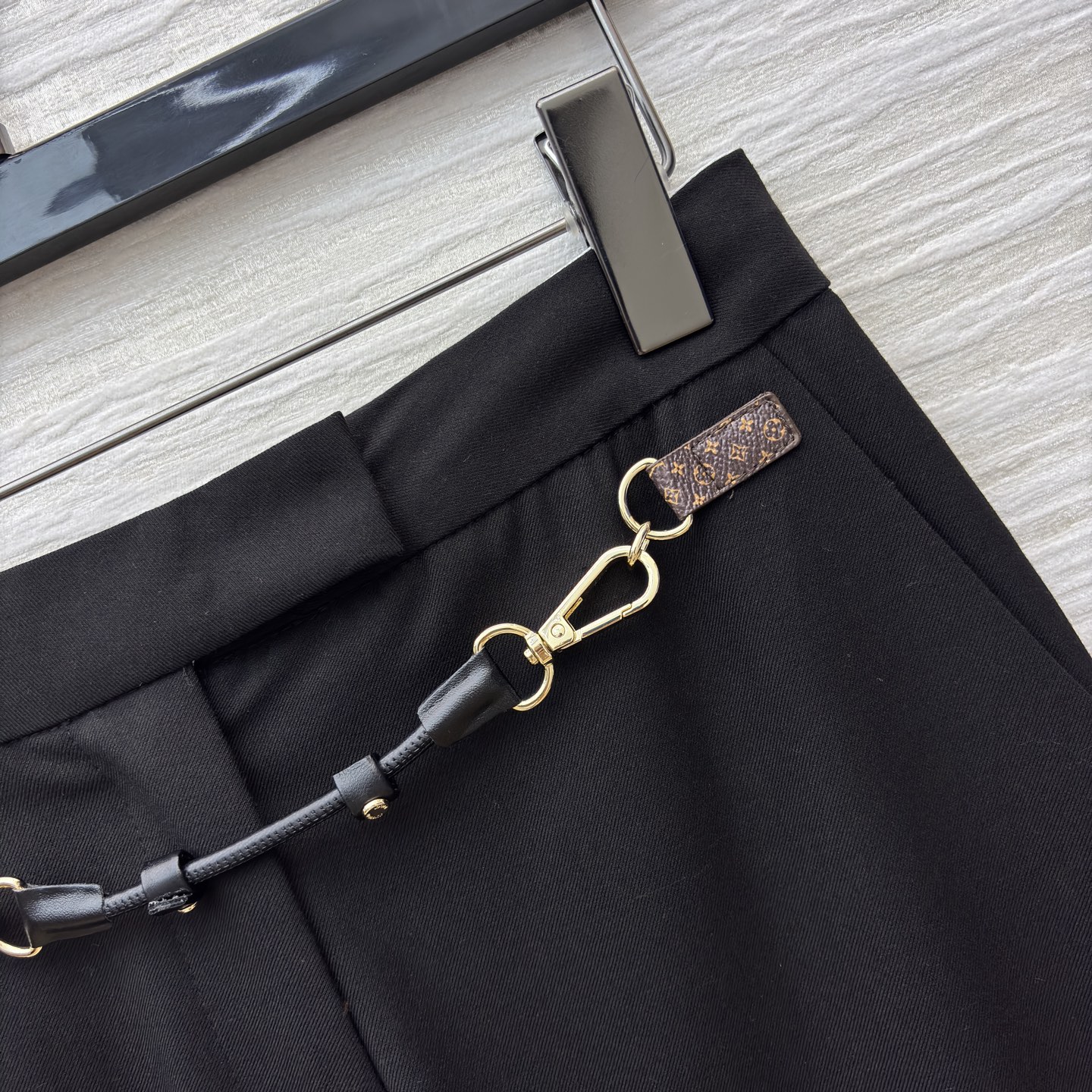 L家 皮扣设计黑色微喇西裤 腰间金属链条装饰瞬间打破单调 为职场穿搭注入个性巧思 利落版型修饰腿型 无论