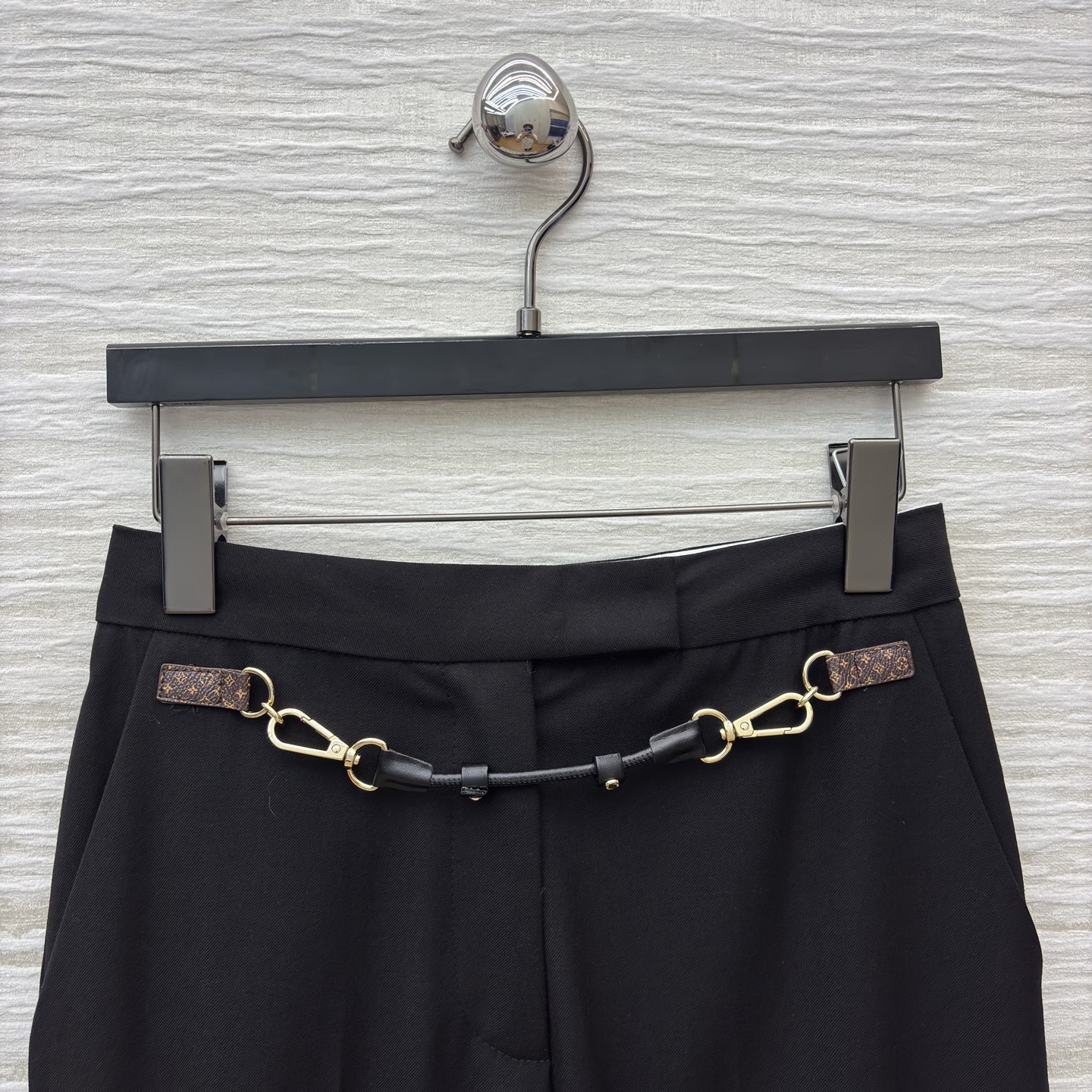 L家 皮扣设计黑色微喇西裤 腰间金属链条装饰瞬间打破单调 为职场穿搭注入个性巧思 利落版型修饰腿型 无论