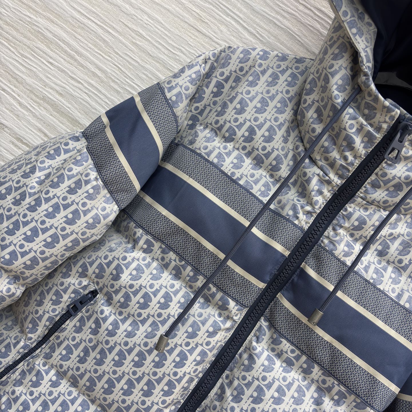 D家 老花连帽羽绒服 冬日高奢御寒典范 满幅Oblique老花贯穿衣身 是品牌基因的高调宣言 藏青条纹拼