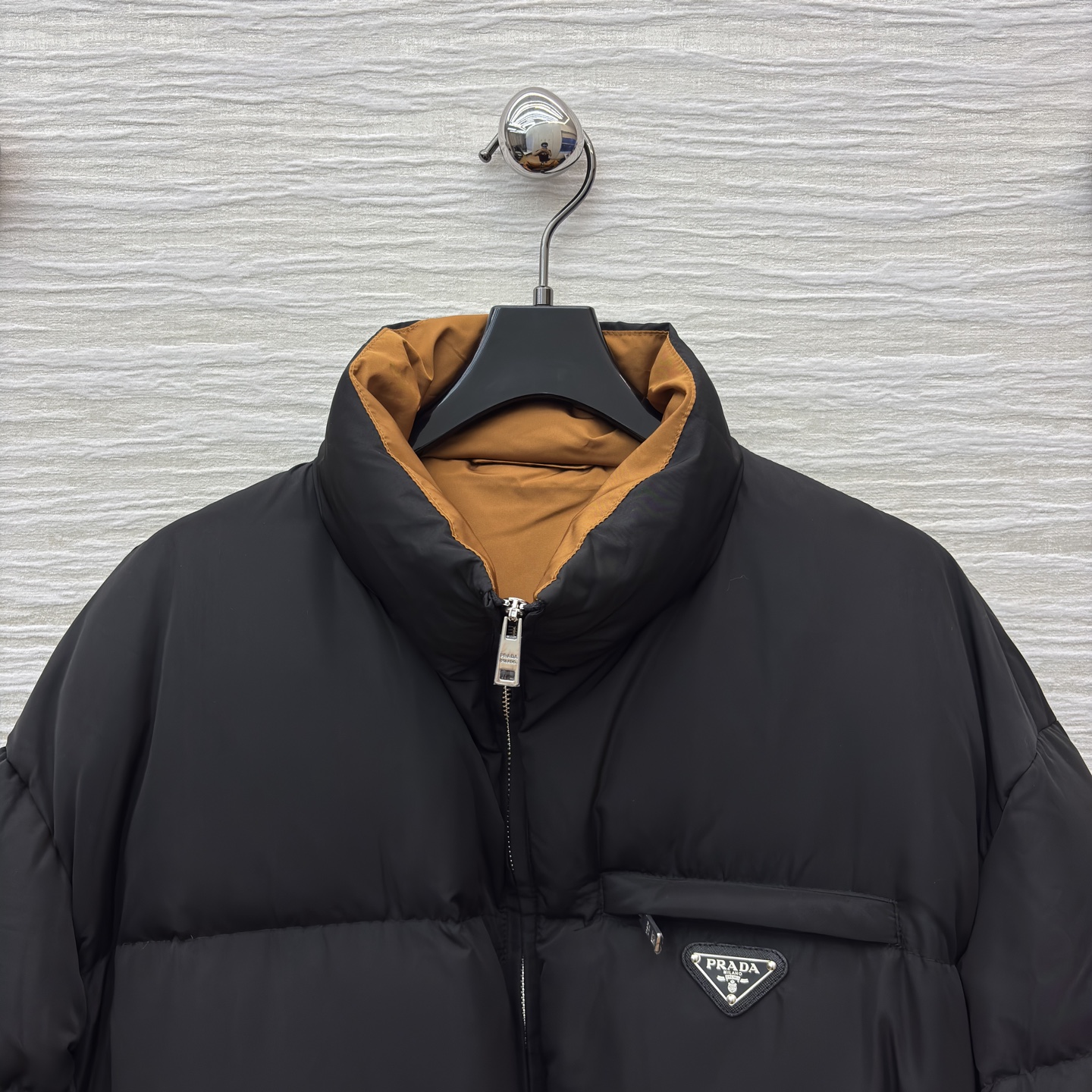 PD 25秋冬 立领黑色羽绒服 是冬日里的时尚“暖盾” 立领设计抵御寒风 腰带收腰勾勒身形 标志性三角标