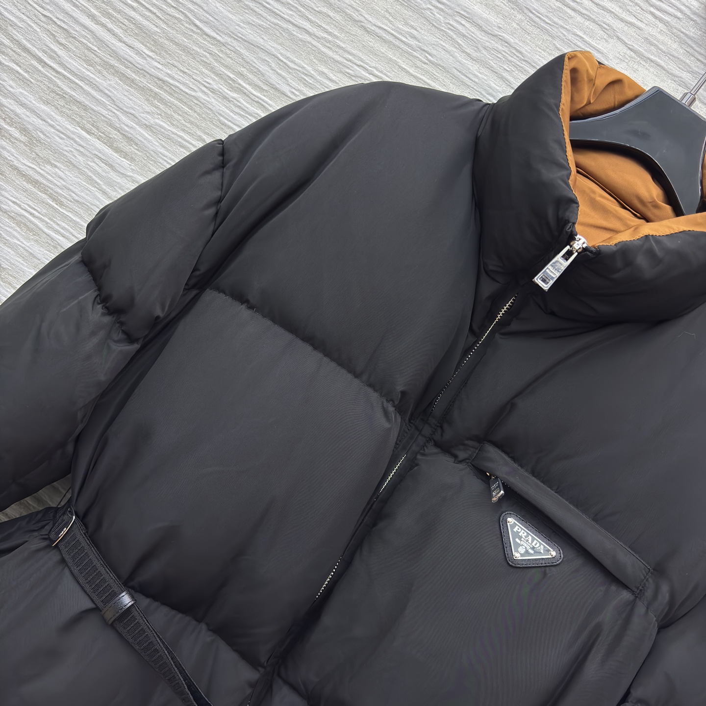 PD 25秋冬 立领黑色羽绒服 是冬日里的时尚“暖盾” 立领设计抵御寒风 腰带收腰勾勒身形 标志性三角标