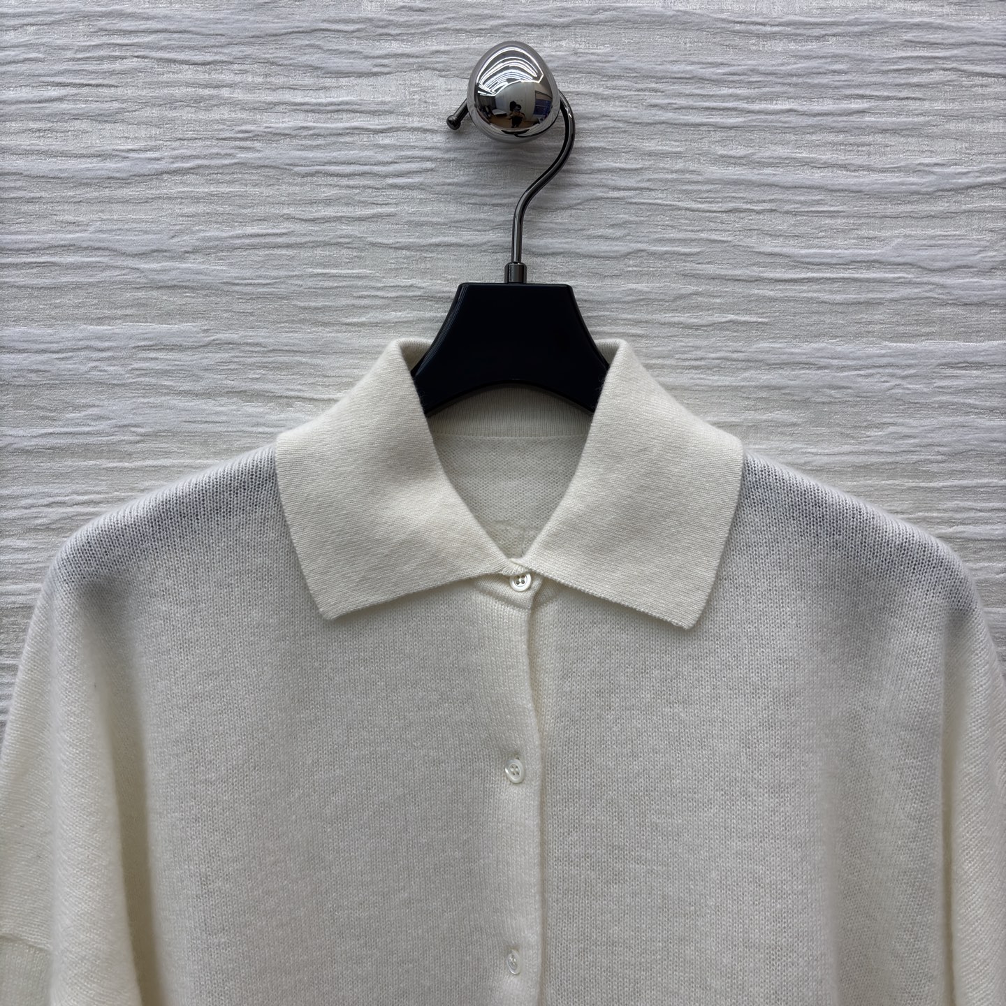 ES米白色羊绒开衫 是温柔与精致的邂逅 经典翻领单排扣设计简约大气 下摆处的镂空蕾丝花纹如繁花绽放 细腻