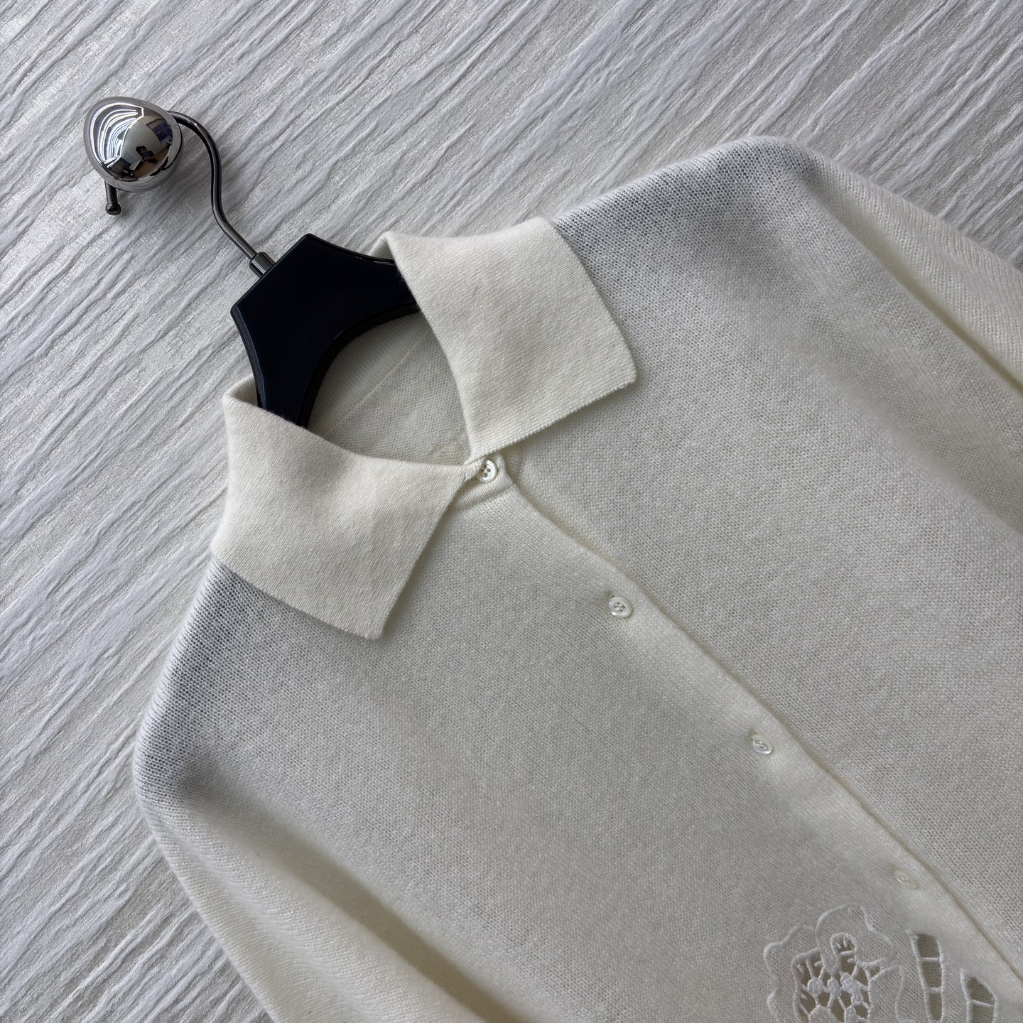 ES米白色羊绒开衫 是温柔与精致的邂逅 经典翻领单排扣设计简约大气 下摆处的镂空蕾丝花纹如繁花绽放 细腻