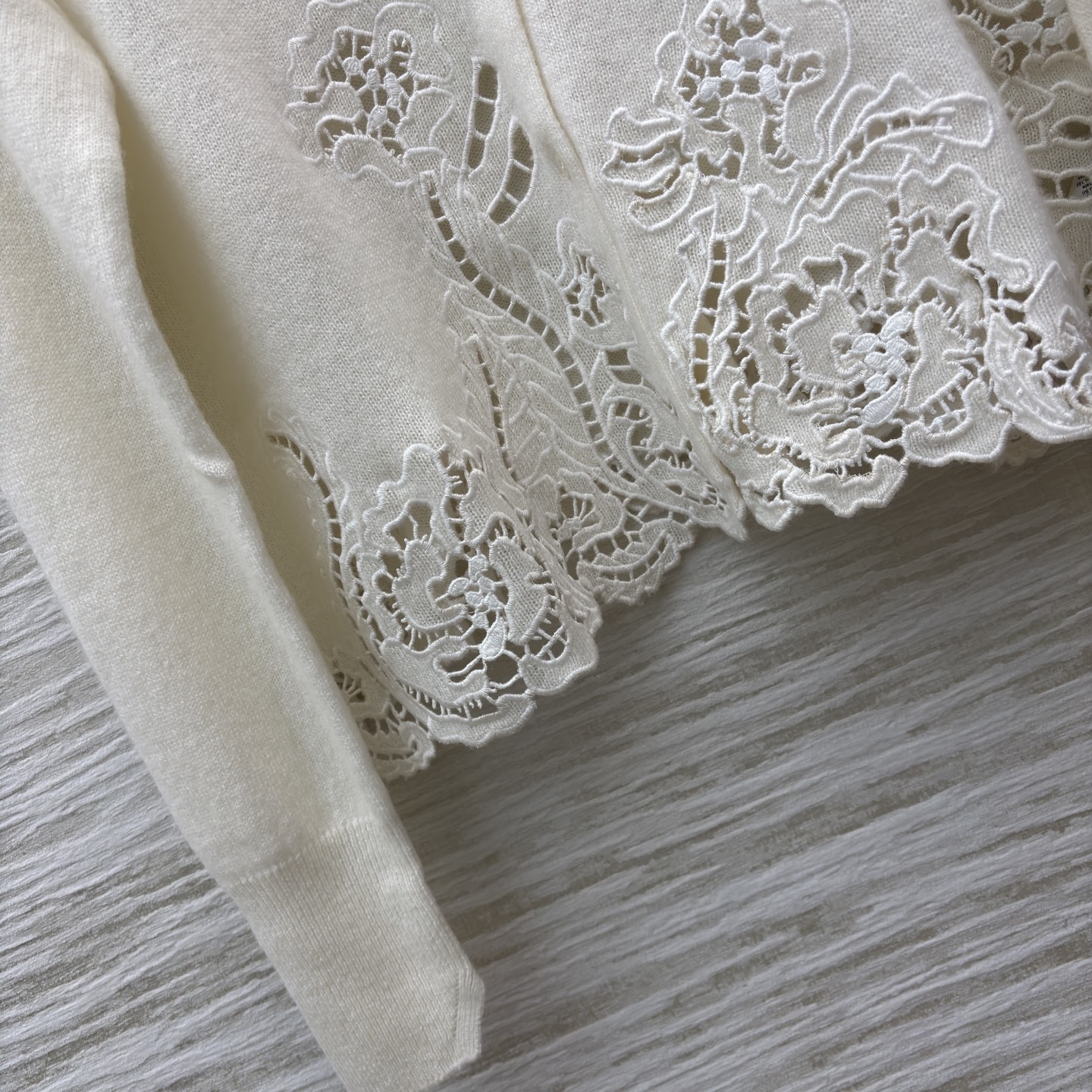 ES米白色羊绒开衫 是温柔与精致的邂逅 经典翻领单排扣设计简约大气 下摆处的镂空蕾丝花纹如繁花绽放 细腻