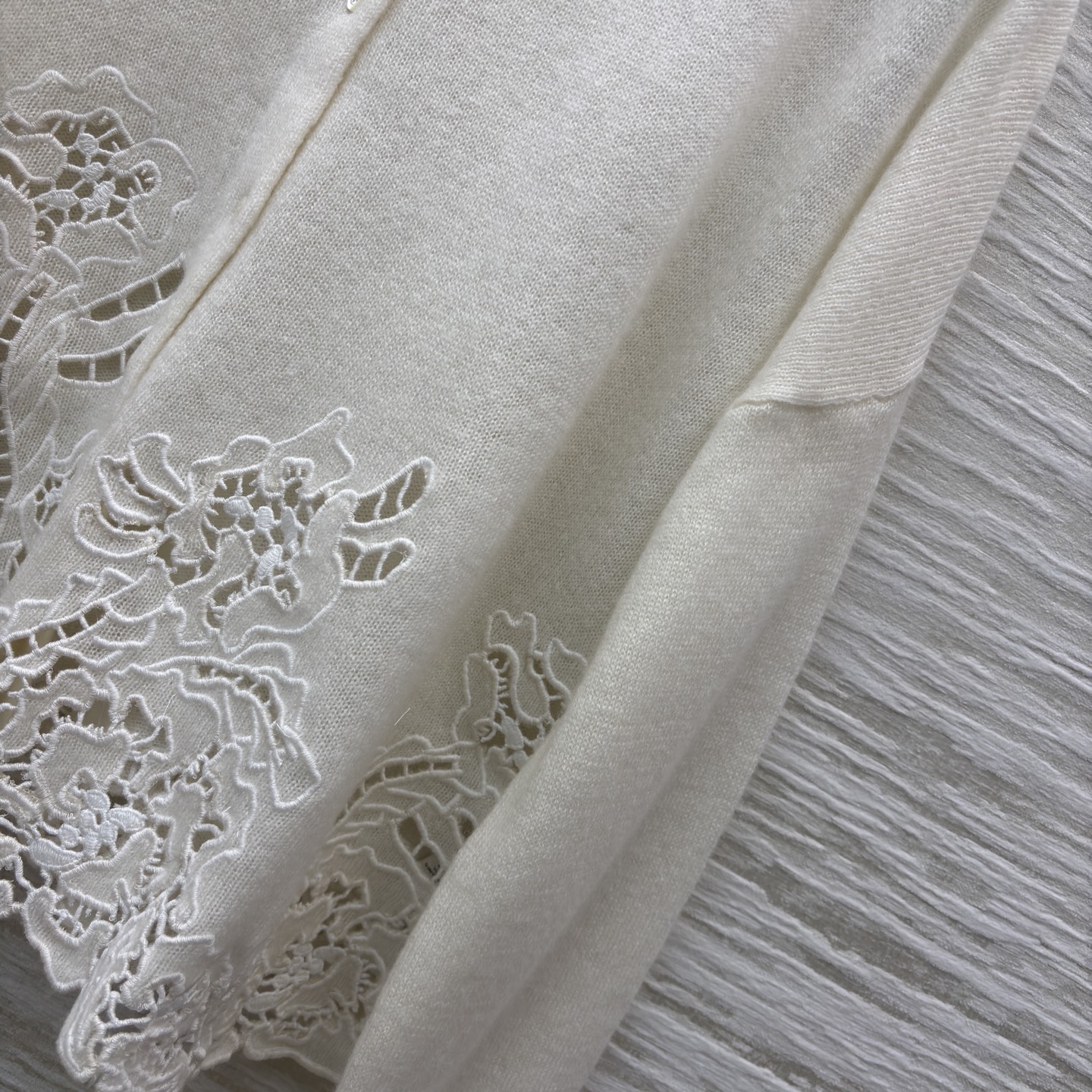 ES米白色羊绒开衫 是温柔与精致的邂逅 经典翻领单排扣设计简约大气 下摆处的镂空蕾丝花纹如繁花绽放 细腻