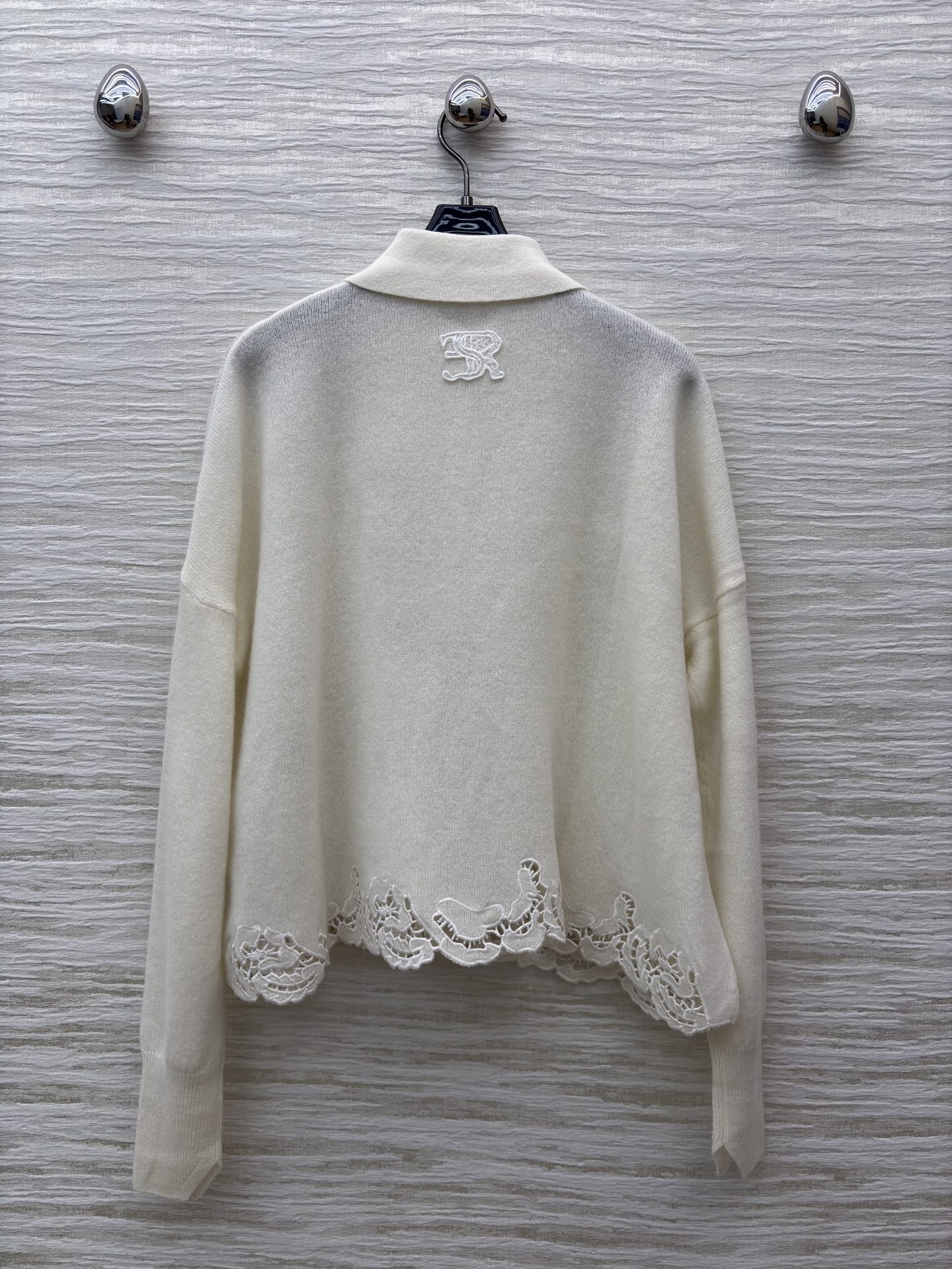 ES米白色羊绒开衫 是温柔与精致的邂逅 经典翻领单排扣设计简约大气 下摆处的镂空蕾丝花纹如繁花绽放 细腻