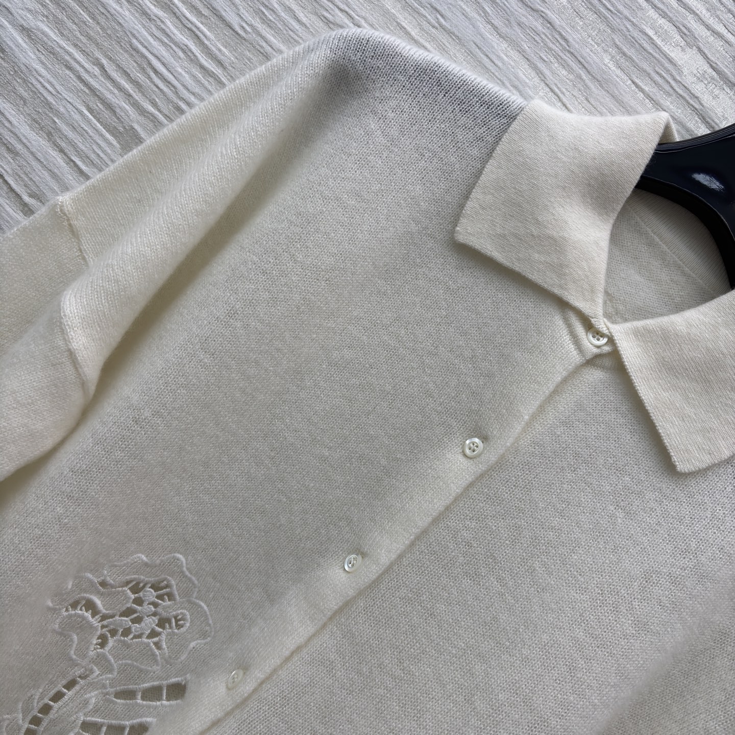 ES米白色羊绒开衫 是温柔与精致的邂逅 经典翻领单排扣设计简约大气 下摆处的镂空蕾丝花纹如繁花绽放 细腻