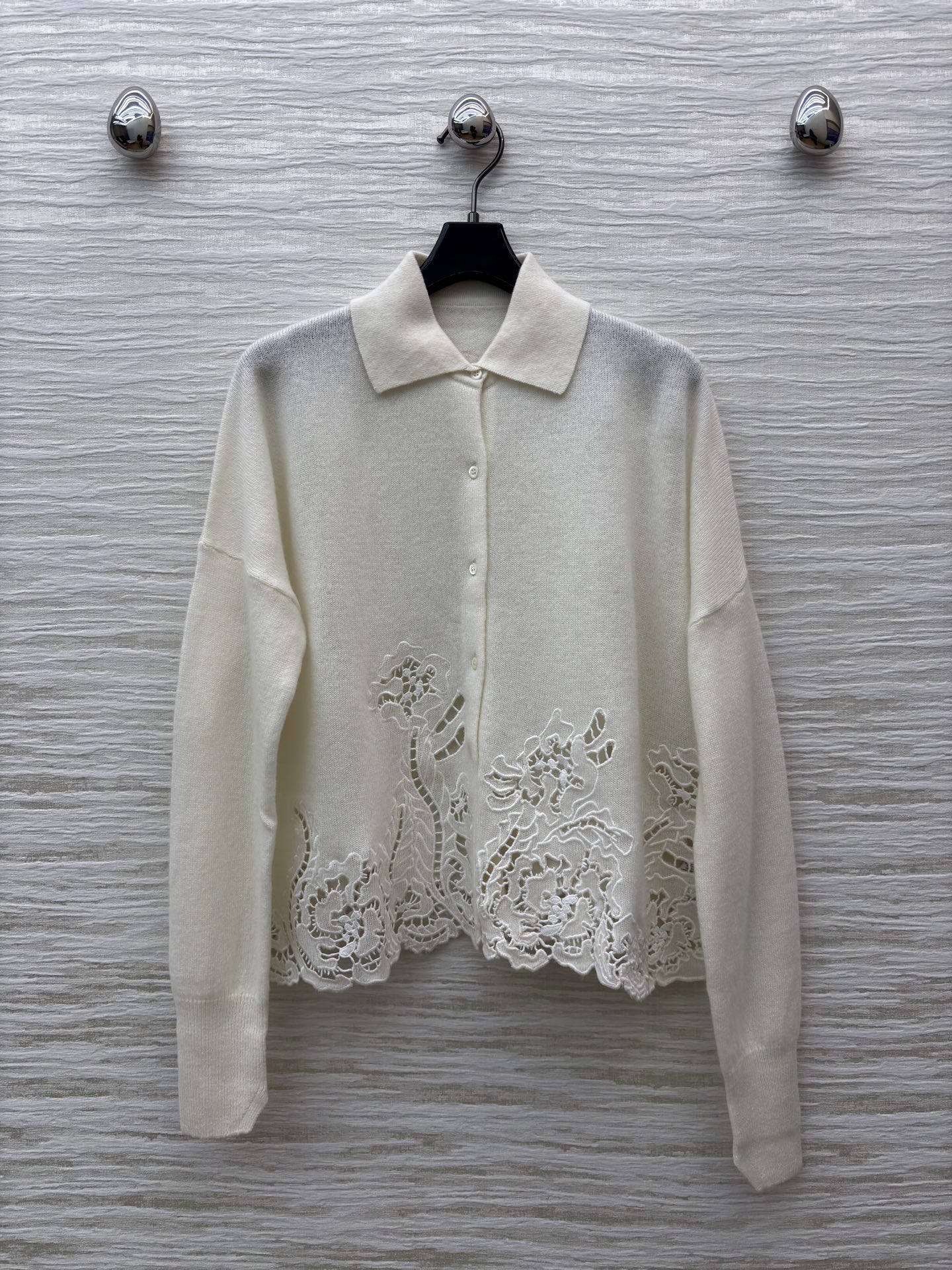 ES米白色羊绒开衫 是温柔与精致的邂逅 经典翻领单排扣设计简约大气 下摆处的镂空蕾丝花纹如繁花绽放 细腻