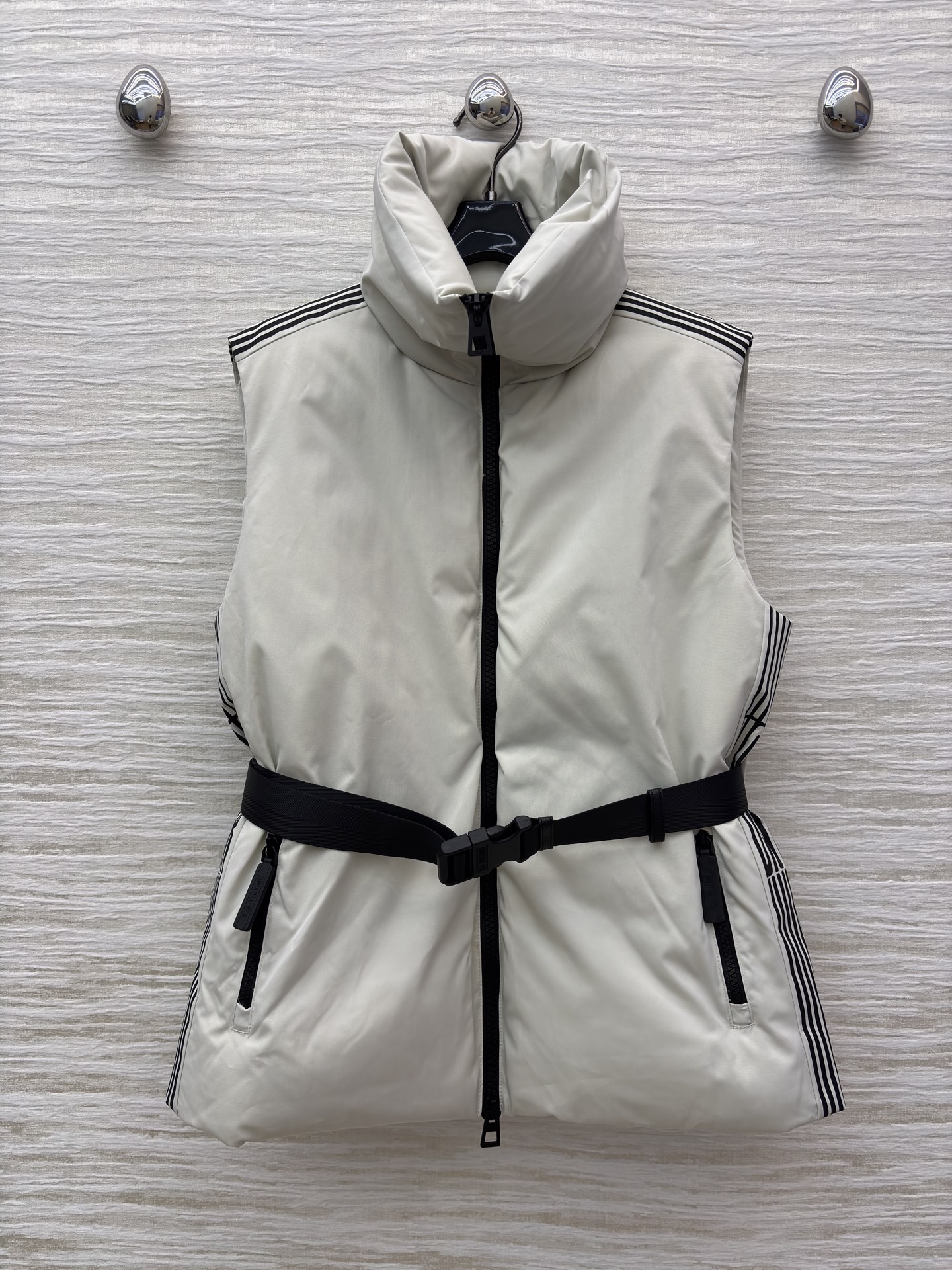 D家 立领腰带羽绒马甲 是秋冬造型的“显瘦神器” 自带极简质感 黑色拉链与腰带收出利落腰线 侧边条纹细节