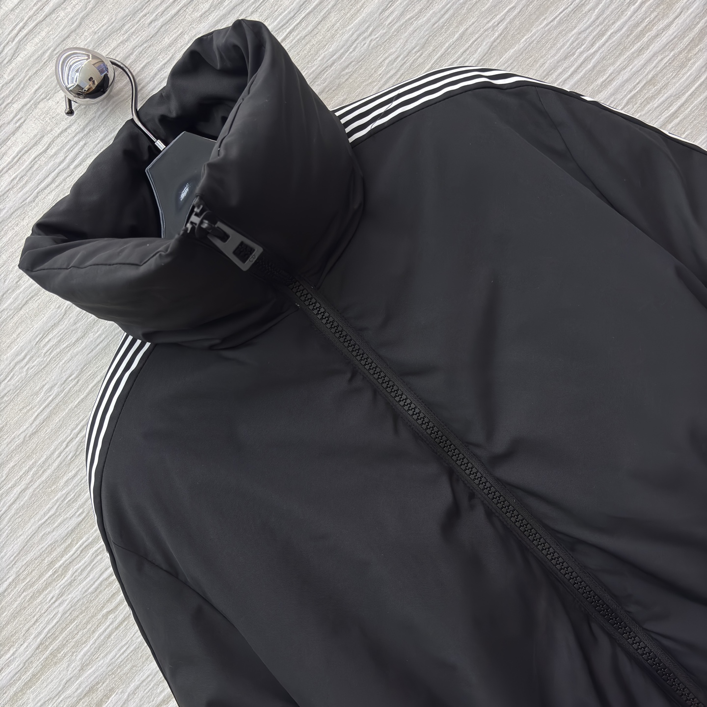 D家 立领收腰羽绒服 是冬日酷感穿搭的首选 立领收腰腰带勾勒利落身形 侧边条纹细节打破纯黑沉闷 蓬松白鸭