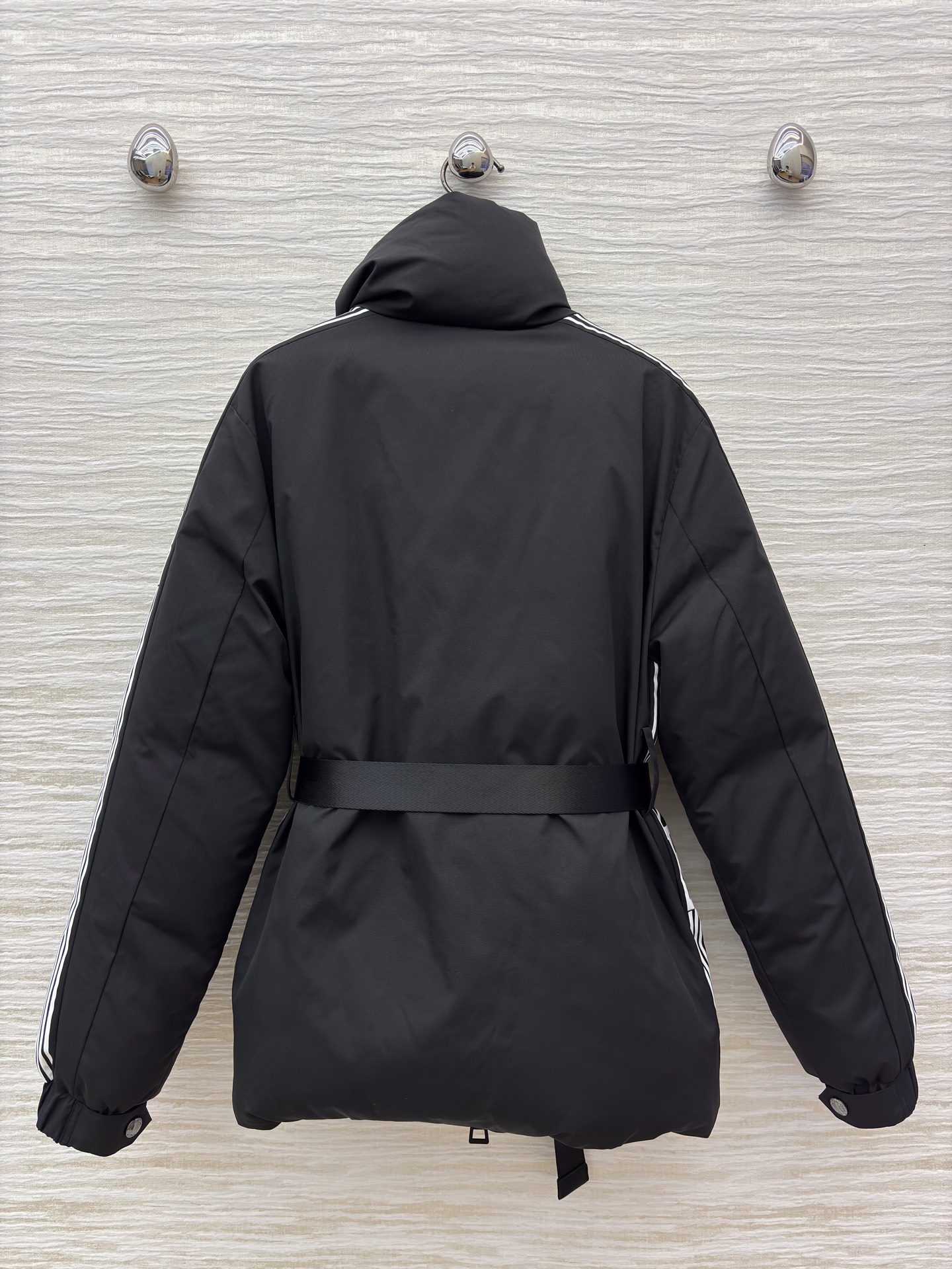 D家 立领收腰羽绒服 是冬日酷感穿搭的首选 立领收腰腰带勾勒利落身形 侧边条纹细节打破纯黑沉闷 蓬松白鸭