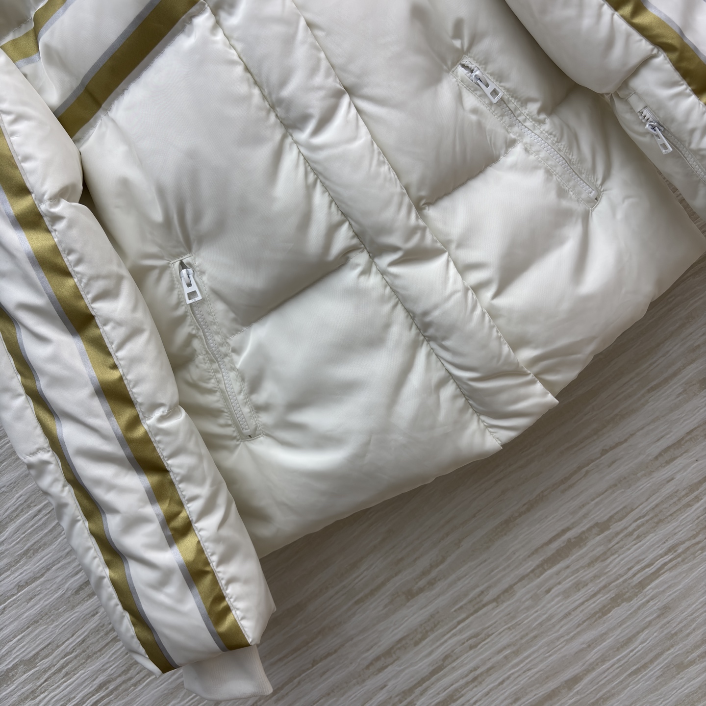 D家 撞色连帽羽绒服 是冬日里的温柔铠甲 米白底色衬出干净氛围 金调条纹与侧边装饰点亮细节 连帽设计裹紧