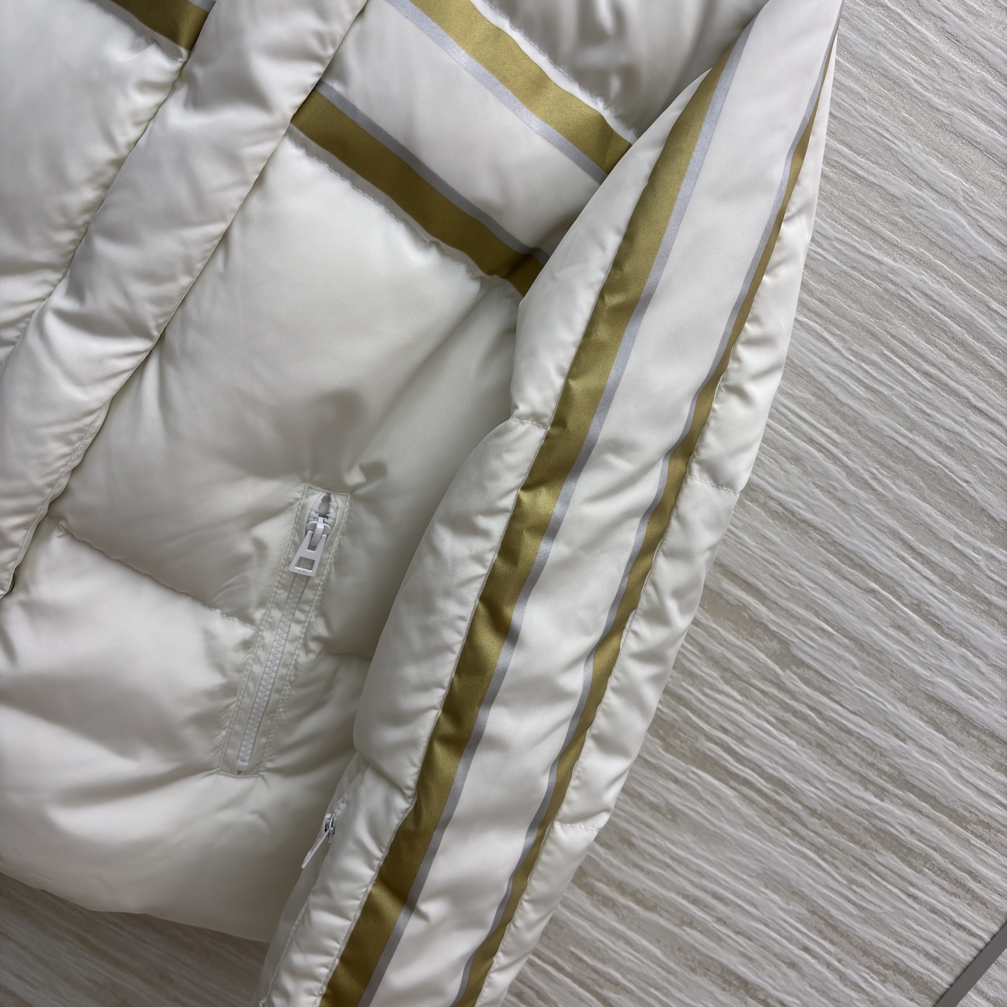 D家 撞色连帽羽绒服 是冬日里的温柔铠甲 米白底色衬出干净氛围 金调条纹与侧边装饰点亮细节 连帽设计裹紧