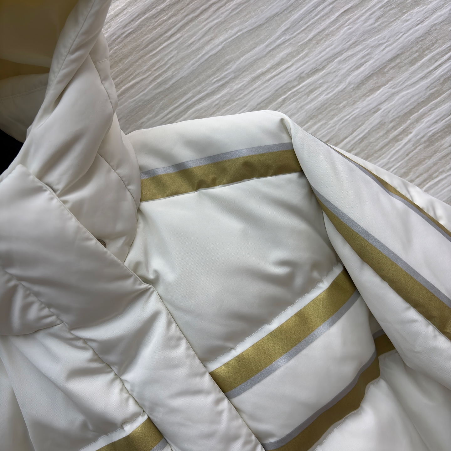 D家 撞色连帽羽绒服 是冬日里的温柔铠甲 米白底色衬出干净氛围 金调条纹与侧边装饰点亮细节 连帽设计裹紧