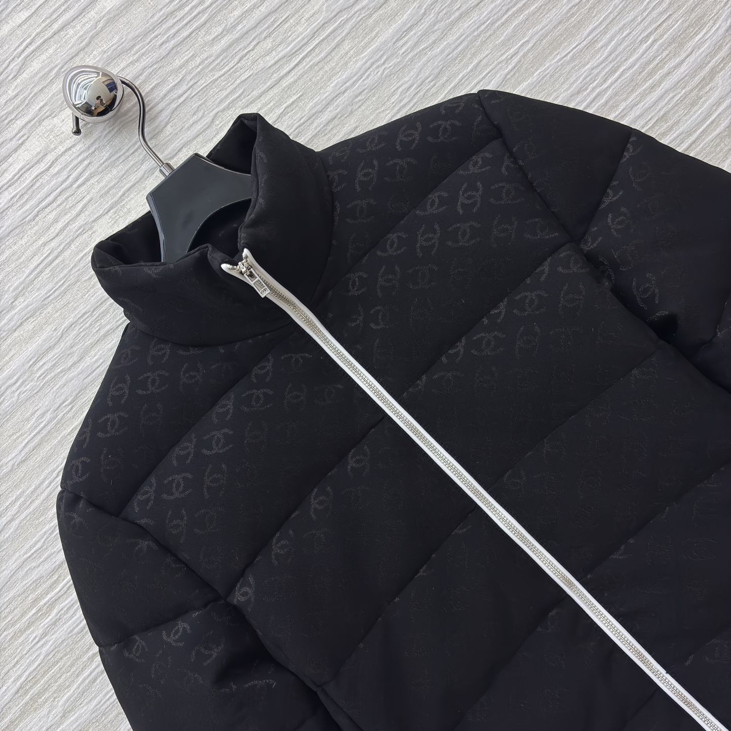 香家黑色立领羽绒服 满印暗纹双C低调衬质感 横向绗缝搭配银白拉链撞色 利落短款版型适配各种内搭 日常出街