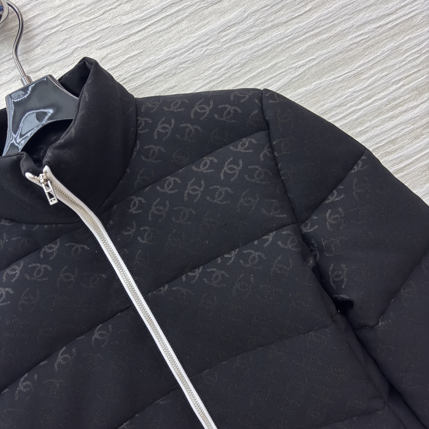 香家黑色立领羽绒服 满印暗纹双C低调衬质感 横向绗缝搭配银白拉链撞色 利落短款版型适配各种内搭 日常出街