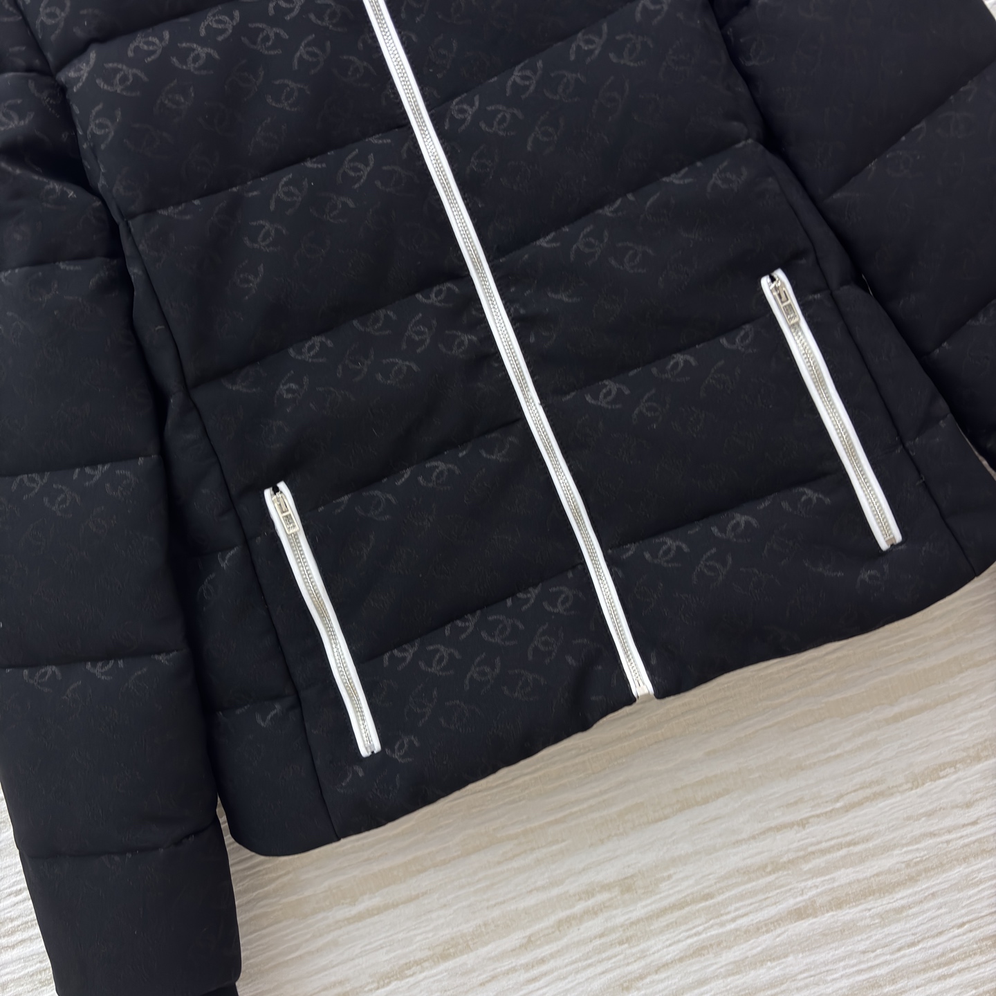 香家黑色立领羽绒服 满印暗纹双C低调衬质感 横向绗缝搭配银白拉链撞色 利落短款版型适配各种内搭 日常出街