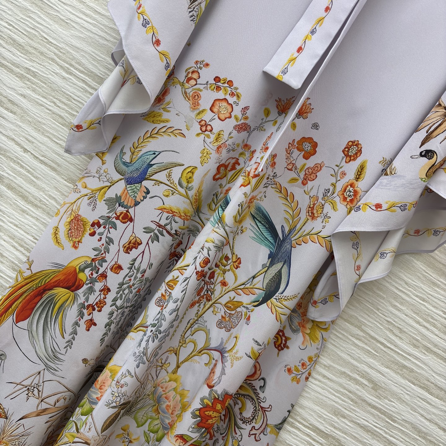 花鸟真丝印花长裙 底色干净柔和 缤纷花鸟图案栩栩如生 领口蝴蝶结设计温婉雅致 斗篷式飞袖飘逸灵动 垂顺的