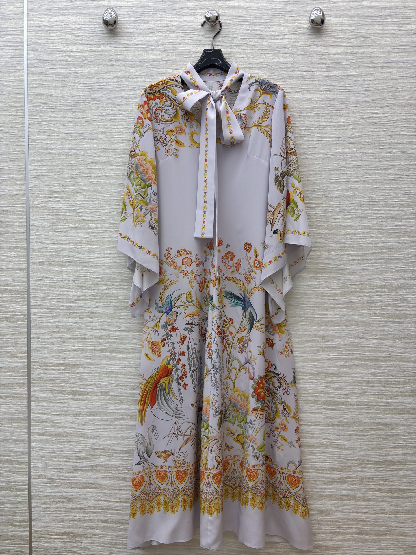 花鸟真丝印花长裙 底色干净柔和 缤纷花鸟图案栩栩如生 领口蝴蝶结设计温婉雅致 斗篷式飞袖飘逸灵动 垂顺的