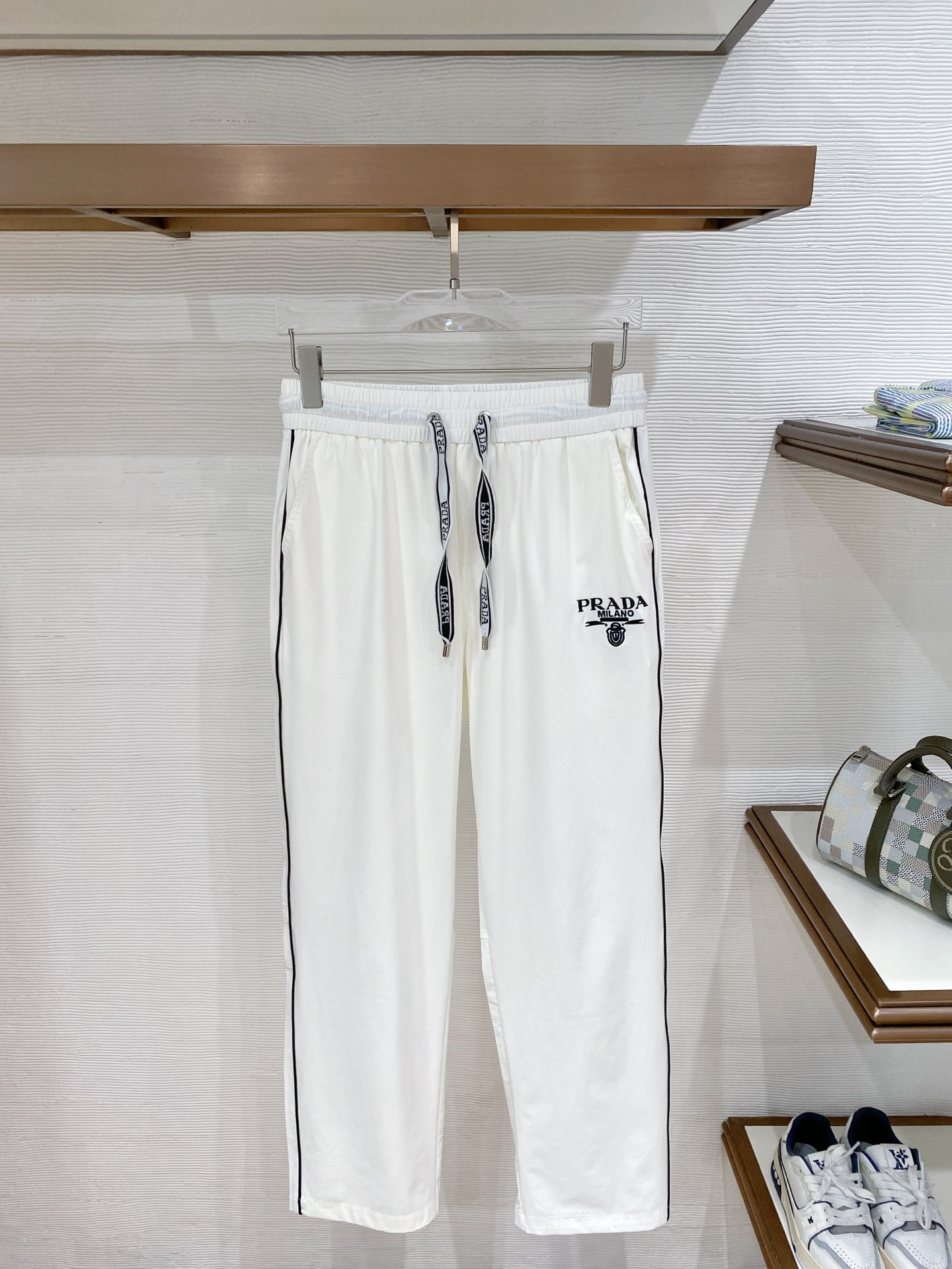 NO:842004,.Prada summer light luxury straight casual pants 'Italian style, cool style' inherits the high-end aesthetics of Milan and is specially designed to create light luxury casual pants for midsummer. The high-definition ice-like drape fabric is selected, soft and silky to the touch, with breathable and cool properties, light and not weighing down, bid farewell to the hot and sticky summer, and keep you comfortable at all times.  The neat straight-leg trousers shape accurately modifies the leg lines, hides the body fat and makes the body slimmer, and has a relaxed old-money style. The contrasting webbing on the side outlines the outline, breaks the monotony and adds a refined level, showing the ingenuity of Italian minimalist design.  Customized brand logo drawstrings are paired with classic logo prints on the trousers, re-engraving classic visual symbols, and low-key revealing the recognition of luxury brands. The classic black and white two-tone color is versatile and can be easily adapted to T-shirts, Polo, shirts and other multiple items. It can be used in all scenes of commuting, traveling, and daily leisure. It reshapes the summer men's style with texture. It is the summer trousers that high-end men need. Color Black White Size M-3Xl, prada, shirts, tees, t-shirt,19860909.普拉达 夏季轻奢直筒休闲裤 「意式格调 凉感型格」 承袭米兰高阶美学底蕴,专为盛夏打造轻奢休闲裤履.甄选高定冰感垂顺面料,触感柔润丝滑,自带透气凉感属性,轻盈不压身,告别夏日闷热黏腻,时刻保持舒爽体感. 利落直筒裤型,精准修饰腿部线条,不挑身形藏肉显瘦,自带松弛老钱风气场；侧边撞色织带勾勒轮廓,打破单调更添精致层次,尽显意式极简设计巧思. 定制品牌标识抽绳搭配裤身经典徽标印花,复刻经典视觉符号,低调流露奢牌辨识度.黑白经典双色百搭不出错,轻松适配T恤、Polo、衬衫等多元单品,通勤、出游、日常休闲全场景驾驭,以质感重塑夏日男士穿搭格调,是高阶品味男士的夏季刚需神裤. 颜色黑色 白色 码数M-3Xl,,prada,shirts,tees，t-shirt,,Men's clothing