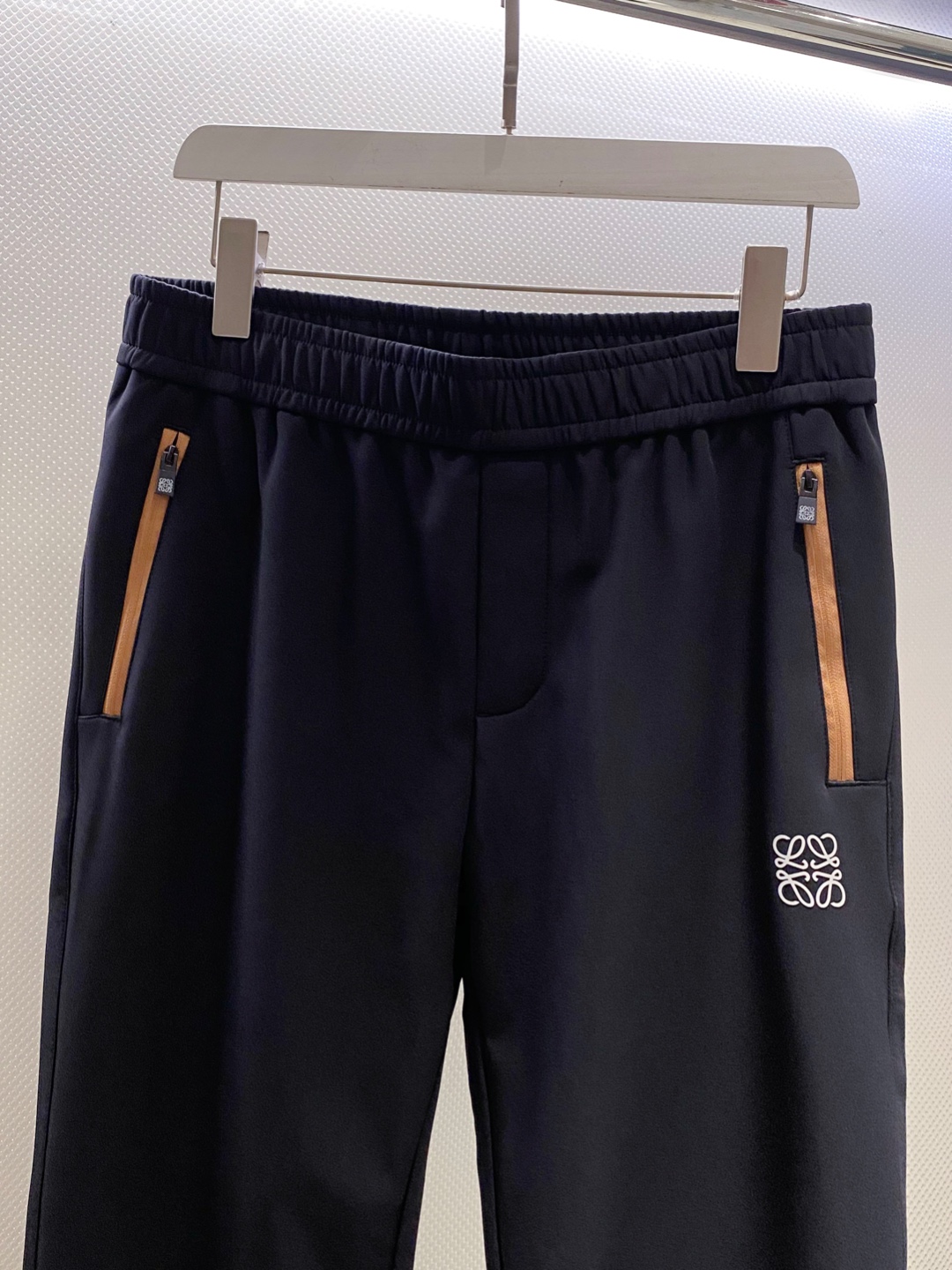 LOE~经典logo刺绣松紧腰散口休闲裤
秋冬新品
精选透气耐磨的优质复合面料，触感柔软亲肤，透气性佳，面料自带轻微垂坠感，不易起皱变形，日常打理更省心。
前经典logo标识刺绣点缀，细腻工整的针脚勾勒出质感，立体感十足，既避免了大面积印花的浮夸，又能通过小细节提升整体造型的辨识度，低调中尽显高贵品味。斜拉口袋大胆的撞色设计是点睛之笔，打破基础款的单调，轻松点亮整体造型，不仅实用能装，更添几分利落动感，日常取物便捷又时髦。
采用利落直筒剪裁，修饰腿型效果出众，能巧妙掩盖腿粗、腿型不直等问题，拉长腿部线条，让身材比例更显优越。无论是搭配简单T恤还是休闲卫衣，便外套，都能瞬间提升吸睛度。松紧腰头不挑身材，穿脱无压力，久穿也不会有束缚感，散口裤型适配多种鞋款，通勤、逛街、约会都能穿，轻松拿捏随性自在的日常风格。

颜色：黑色
规格：M&mdash;XXXL
    P280
L码:腰围78.臀围104.裆长30.裤长99.裤脚口36
XL码：腰围81.臀围108.裆长31.裤长100.裤脚口37