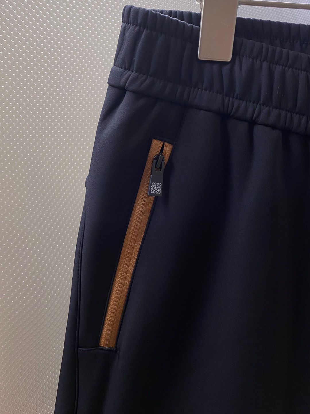 LOE~经典logo刺绣松紧腰散口休闲裤
秋冬新品
精选透气耐磨的优质复合面料，触感柔软亲肤，透气性佳，面料自带轻微垂坠感，不易起皱变形，日常打理更省心。
前经典logo标识刺绣点缀，细腻工整的针脚勾勒出质感，立体感十足，既避免了大面积印花的浮夸，又能通过小细节提升整体造型的辨识度，低调中尽显高贵品味。斜拉口袋大胆的撞色设计是点睛之笔，打破基础款的单调，轻松点亮整体造型，不仅实用能装，更添几分利落动感，日常取物便捷又时髦。
采用利落直筒剪裁，修饰腿型效果出众，能巧妙掩盖腿粗、腿型不直等问题，拉长腿部线条，让身材比例更显优越。无论是搭配简单T恤还是休闲卫衣，便外套，都能瞬间提升吸睛度。松紧腰头不挑身材，穿脱无压力，久穿也不会有束缚感，散口裤型适配多种鞋款，通勤、逛街、约会都能穿，轻松拿捏随性自在的日常风格。

颜色：黑色
规格：M&mdash;XXXL
    P280
L码:腰围78.臀围104.裆长30.裤长99.裤脚口36
XL码：腰围81.臀围108.裆长31.裤长100.裤脚口37