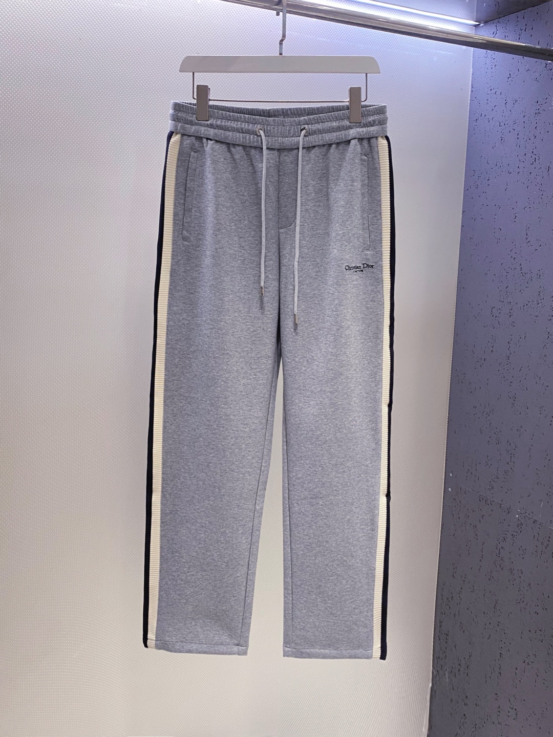 NO:732511,CD~ Modal air cotton straight-leg sweatpants inlaid with webbing on both sides, new arrival in early spring 2026. High-quality modal air-layer fabric, soft and skin-friendly, comfortable and casual. The brand logo letter embroidery logo on the thigh interprets high-luxury leisure, and the stitching is fine and three-dimensional, integrating the high-luxury logo into daily life, and highlighting the identity and style in a low-key manner; the webbing inlay design on both sides of the trouser legs inherits the essence of the D family's classic weaving art. It is elastic and non-restrictive, free and ceremonial.  The neat straight cut modifies the leg lines, adapts to various body shapes, and shows a calm posture when walking. From daily travel to light business scenes, unlock a variety of outfits, making luxury a natural expression of daily life, interpreting men's elegant and fashionable dressing philosophy. Colors: floral gray, dark blue Specifications M--XXXL L size: waist 76. crotch length 32. trouser opening 42. hip 108. trouser length 108  XL size: waist 79, crotch length 33, leg opening 43, hip 112, trouser length 109 w,, dior,19860909CD~两侧织带镶嵌莫代尔空气棉直筒卫裤 2026早春新品 客供优质莫代尔空气层面料,柔软亲肤,舒适随性.大腿处品牌logo字母刺绣徽标诠释高奢休闲,针脚细密立体,将高奢标识融于日常,低调间彰显身份格调；裤腿两侧织带嵌花设计,承袭D家经典织艺精髓,弹性贴合不束缚,自在兼具仪式感. 利落直筒剪裁修饰腿部线条,适配各种身形,行走间尽展从容姿态.从日常出行到轻商务场景,解锁多种穿搭,让奢华成为日常的自然表达,诠释男士优雅时尚穿搭哲学. 颜色花灰色、深蓝色 规格M--XXXL  L码:腰围76.裆长32.裤脚口42.臀围108.裤长108 XL码:腰围79.裆长33.裤脚口43.臀围112.裤长109 w,,dior,,Men's clothing