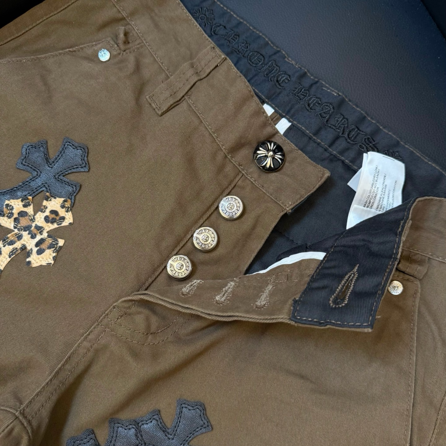 款号:D336 Chrome Hearts CH克罗心棕色豹纹拼皮牛仔裤 散发着不羁的个性和独特的魅力.每一处磨损和破洞都是精心设计,呈现出一种独特的艺术感.选用进口牛仔面料,经过超重工水洗和破坏处理,裤身展现出上身超酷的效果 这不仅仅是一条牛仔裤,更是一种态度的表达.克罗心以其独特的设计理念和对细节的极致追求,打破传统界限,定义了新时代的牛仔裤风潮.裤身采用双层梭织面料,搭配订制五金,展现出无敌好看的独特款式,使每一位穿戴者都成为时尚的焦点. 进口牛仔面料 超重工水洗破坏 上身超酷!订制五金 无敌好看的款 制作工艺很难 高街感满满 Color:棕色 尺寸参考: 28裤长101腰围78 30裤长103腰围82 32裤长105腰围86 34裤长106腰围90