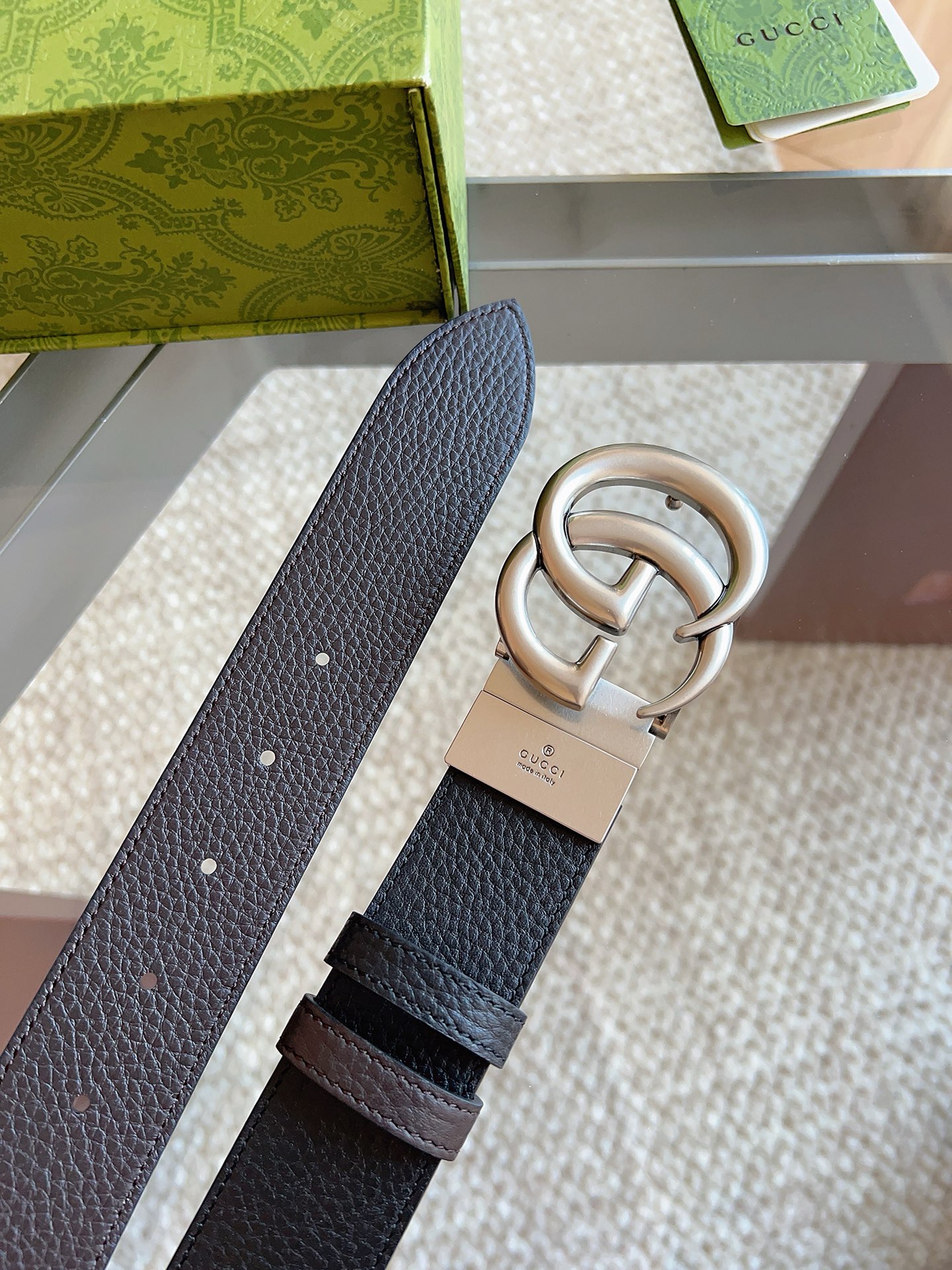 GUCCI 这款双面皮革腰带采用荔枝纹皮革材质，饰以经典双G搭扣，该配件灵感源自品牌辉煌的70年代典藏设