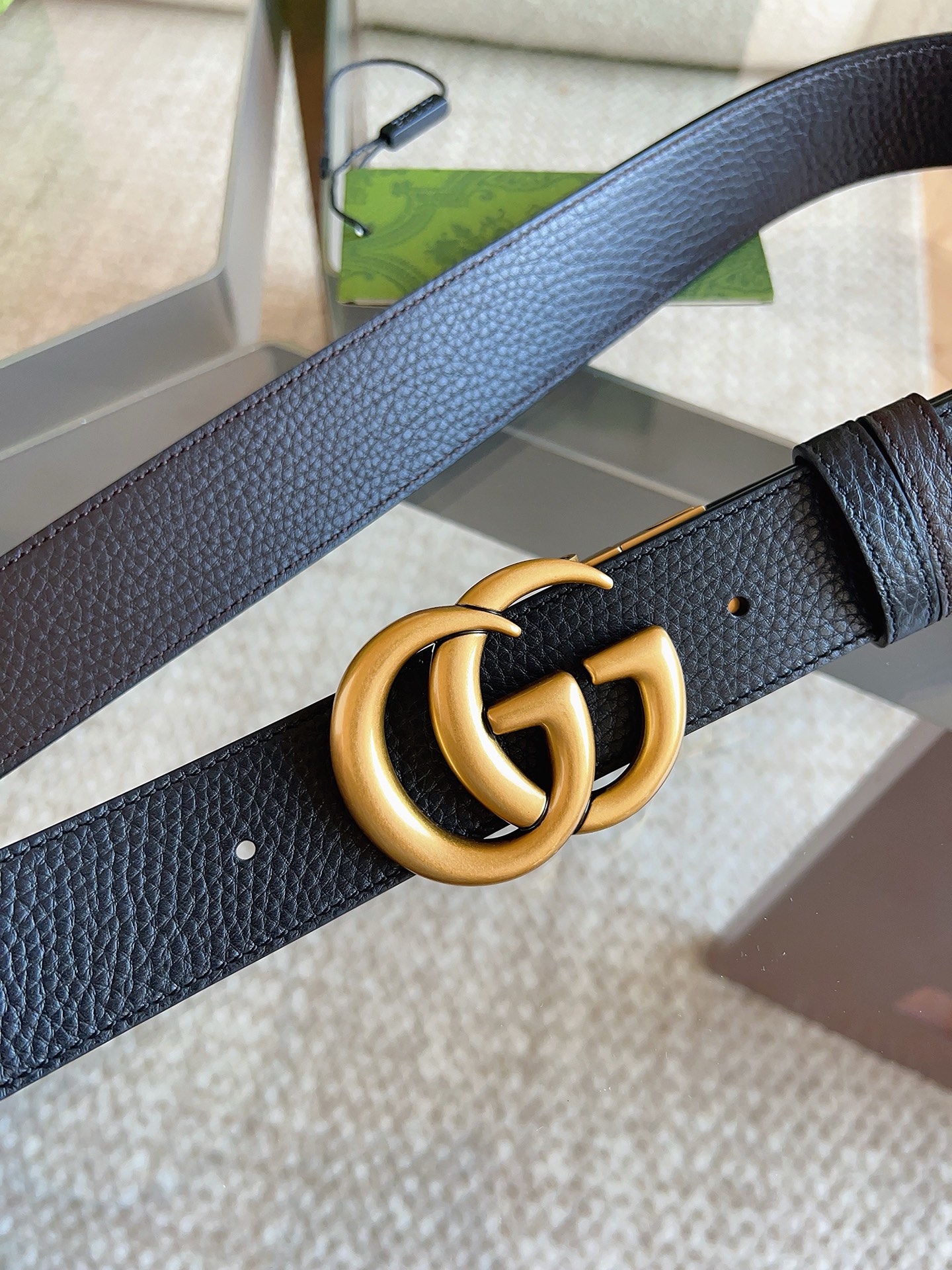 GUCCI 这款双面皮革腰带采用荔枝纹皮革材质，饰以经典双G搭扣，该配件灵感源自品牌辉煌的70年代典藏设