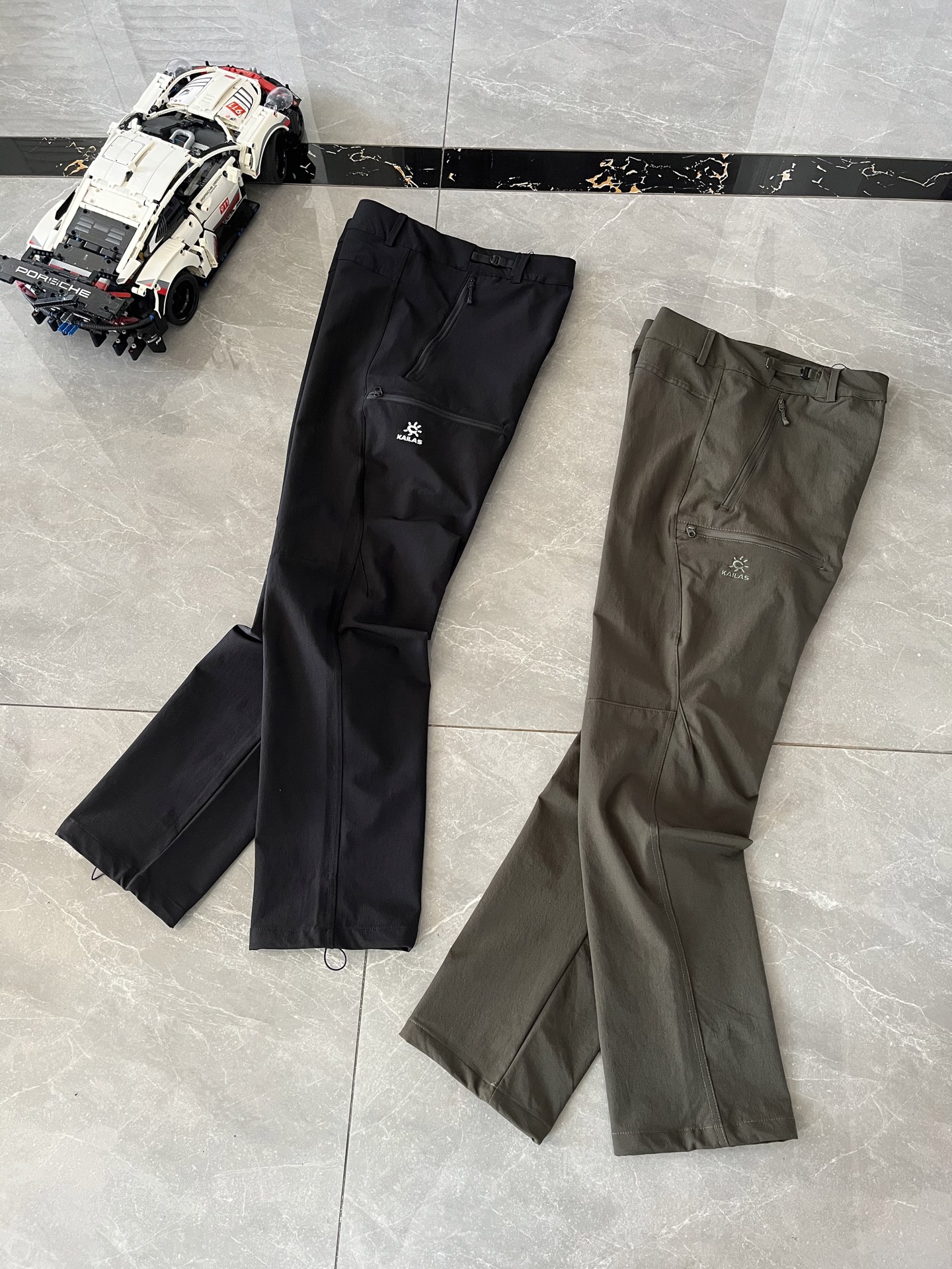 P150    顶尖现货    凯乐石KAILAS T10-X系列运动户外CORDURA耐磨防风专业登山徒步软壳休闲裤
面料 : 采用CORDURA尼龙66材料，易磨损的膝盖和臀部等部位使用高密度CORDURA加强面料，其余区域则用更亲肤的CORDURA面料，既提升了耐用性，又保证了穿着的舒适感。
版型剪裁：运用专业立体剪裁设计，尤其是立体膝位和臀位设计，能减少运动时的束缚感，让穿着者在攀岩、高抬腿等大幅度动作中也能活动自如。 
细节设计：腰头有按扣，方便穿脱，腰侧调节扣可快速调节松紧；设有大容量拉链口袋，安全且方便存取物品；膝盖防鼓包设计，裆部采用钻石立档；脚口有防风抽绳和内置靴带钩，可防止风沙、蚊虫入侵。
透气设计：部分款式在膝窝处设有透气冲孔，有助于散发运动产生的热量和汗水，避免闷热不适。
耐磨性能：CORDURA面料本身就具有高耐磨性，加上膝盖和臀部等部位的加强处理，使得裤子能够经受住长时间徒步、摩擦以及通过荆棘、乱石等复杂路段的考验。
防风防泼水：具备良好的防风性能，能有效阻挡寒风侵入；同时具有一定的防泼水功能，遇到小雨等轻微降水情况时，可短时间内防止水分渗入，保持裤子内部干燥。
 颜色 : 玄青黑  松尾绿
​尺码 : M - 3XL
M腰围76臀围96裤长100
​L腰围80臀围100裤长102
​XL腰围84臀围104裤长104
​2XL腰围88臀围108裤长106
​3XL腰围92臀围112裤长108