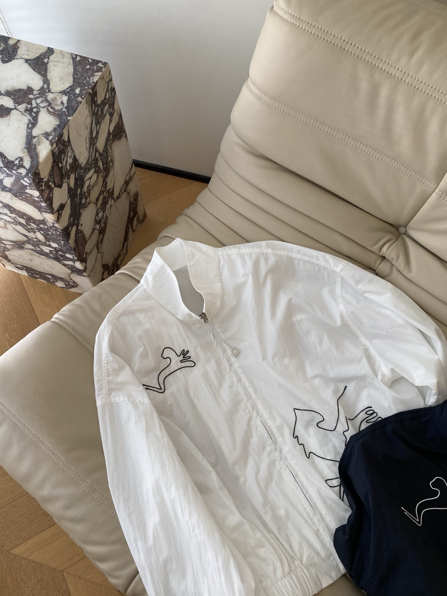 26SS 早春新款立领刺绣防晒夹克采用利落短款立领廓形，纯净白/藏青双调自带清爽滤镜，胸口与衣身小马抽象