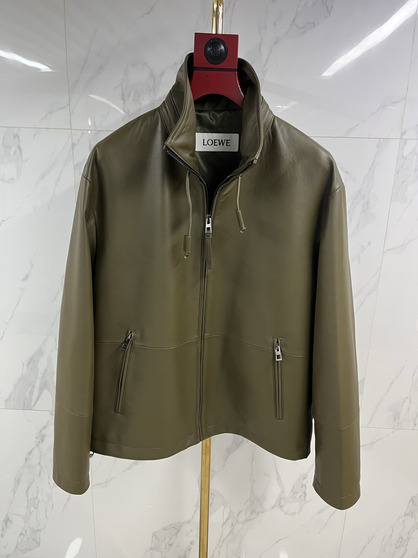 NO:870878,LOEWE  Loewe's new leather jacket for autumn and winter, a new model of men's fashion. At the forefront of fashion, Loewe has always been synonymous with excellent quality and innovative design. In the autumn and winter of this year, Loewe once again used extraordinary creativity to bring a unique sheepskin jacket to men, showing the unique charm of a modern gentleman. This jacket is made of Australian dark green sheepskin.  The color is deep and full of charm, as if you are wearing the mysterious tranquility of the autumn forest on your body. The sheepskin texture is delicate and soft, and has excellent durability. As time goes by, it will increasingly show its unique luster and texture. The slip-on shoulder version of the lapel is the finishing touch of this jacket. The lapel design is simple and neat, adding a bit of sophistication and ease; slipping  The shoulder cut breaks the traditional constraints, weakens the shoulder lines, and creates a casual and relaxed feeling, which can be easily controlled regardless of body shape, perfectly interpreting the fashion attitude of modern men. The threaded design of the hem is not only practical, but also highlights the quality in the details. It is effectively windproof and warm, ensuring that it can remain warm and comfortable in cold weather; at the same time,  The elasticity of the thread makes wearing more comfortable and unrestricted movement. The Loewe brand LOGO patched under the back collar is a low-key and luxurious status symbol. Exquisite craftsmanship and delicate materials complement each other, inadvertently revealing the brand's profound heritage and high-end quality. Only those who know the industry can understand the taste and style at a glance.  Loewe's new autumn and winter men's sheepskin jacket perfectly combines classic elements with modern design. Whether it is a calm atmosphere in business situations or a casual leisure time, it can be easily adapted and become a fashionable must-have item in men's wardrobe. Code number 48——58 code 0, Loewe-clothing, loewe, loewe, jackets & coats, leather jacket, sheepskin,19860909LOEWE 罗意威秋冬新款皮衣,男士时尚新典范在时尚的前沿舞台,罗意威一直是卓越品质与创新设计的代名词.年秋冬,罗意威再次以非凡创意,为男士们带来了一款别具一格的羊皮夹克,尽显现代绅士的独特魅力.这款夹克精选澳洲墨绿色羊皮,色泽深沉而富有韵味,宛如将秋日森林的神秘静谧穿在身上.羊皮质感细腻柔软,兼具卓越的耐用性,随着时间的推移,会愈发彰显出独有的光泽与质感.翻领溜肩版型是这件夹克的点睛之笔,翻领设计简洁利落,增添了几分干练与洒脱；溜肩剪裁打破传统束缚,弱化肩部线条,营造出随性自在的松弛感,无论何种身形都能轻松驾驭,完美诠释现代男士的时尚态度.下摆的螺纹设计不仅实用,更在细节处彰显品质.它有效防风保暖,确保在寒冷天气中也能保持温暖舒适；同时,螺纹的弹性让穿着更加自在,活动不受限制.后衣领下方的罗意威品牌LOGO贴皮,是低调而奢华的身份象征.精致的工艺与细腻的材质相得益彰,不经意间流露出品牌的深厚底蕴与高端品质,只有懂行的人才能一眼洞悉其中的品味与格调 .罗意威秋冬新款男士羊皮夹克,将经典元素与现代设计完美融合,无论是商务场合的沉稳大气,还是休闲时光的自在随性,它都能轻松适配,成为男士们衣橱中的时尚必备单品. 码数48———58编码0,罗意威-服装,loewe,loewe,jackets & coats,leather jacket,sheepskin,,Women's clothing