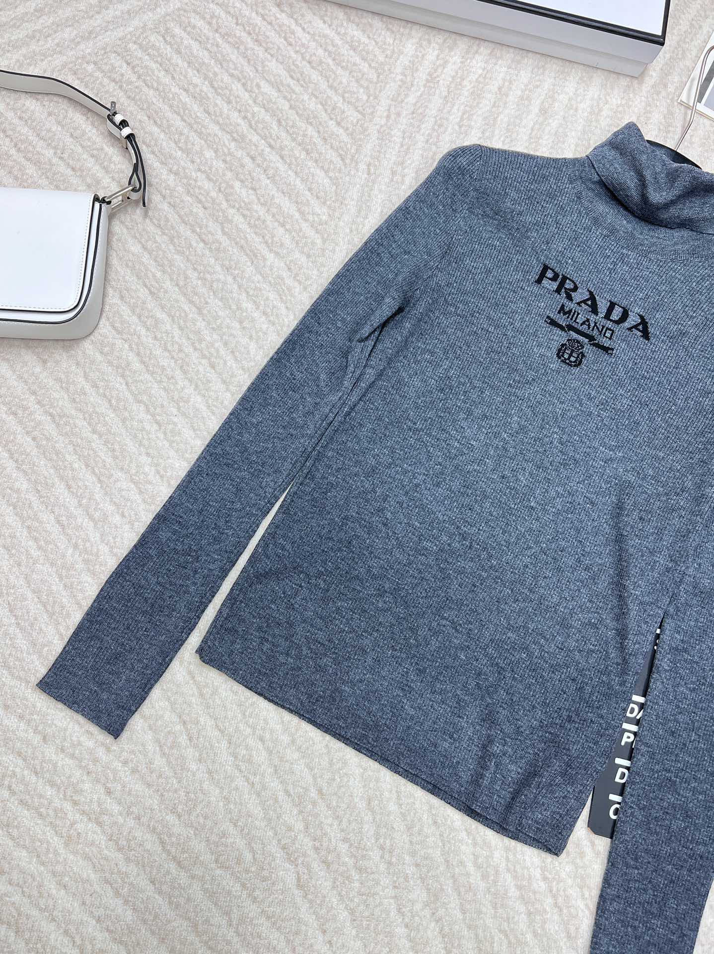 🆕 PRADA 胸口经典logo嵌花高领长袖针织衫，这款修身版型针织长袖源自经典罗纹针织系列 简洁修身版