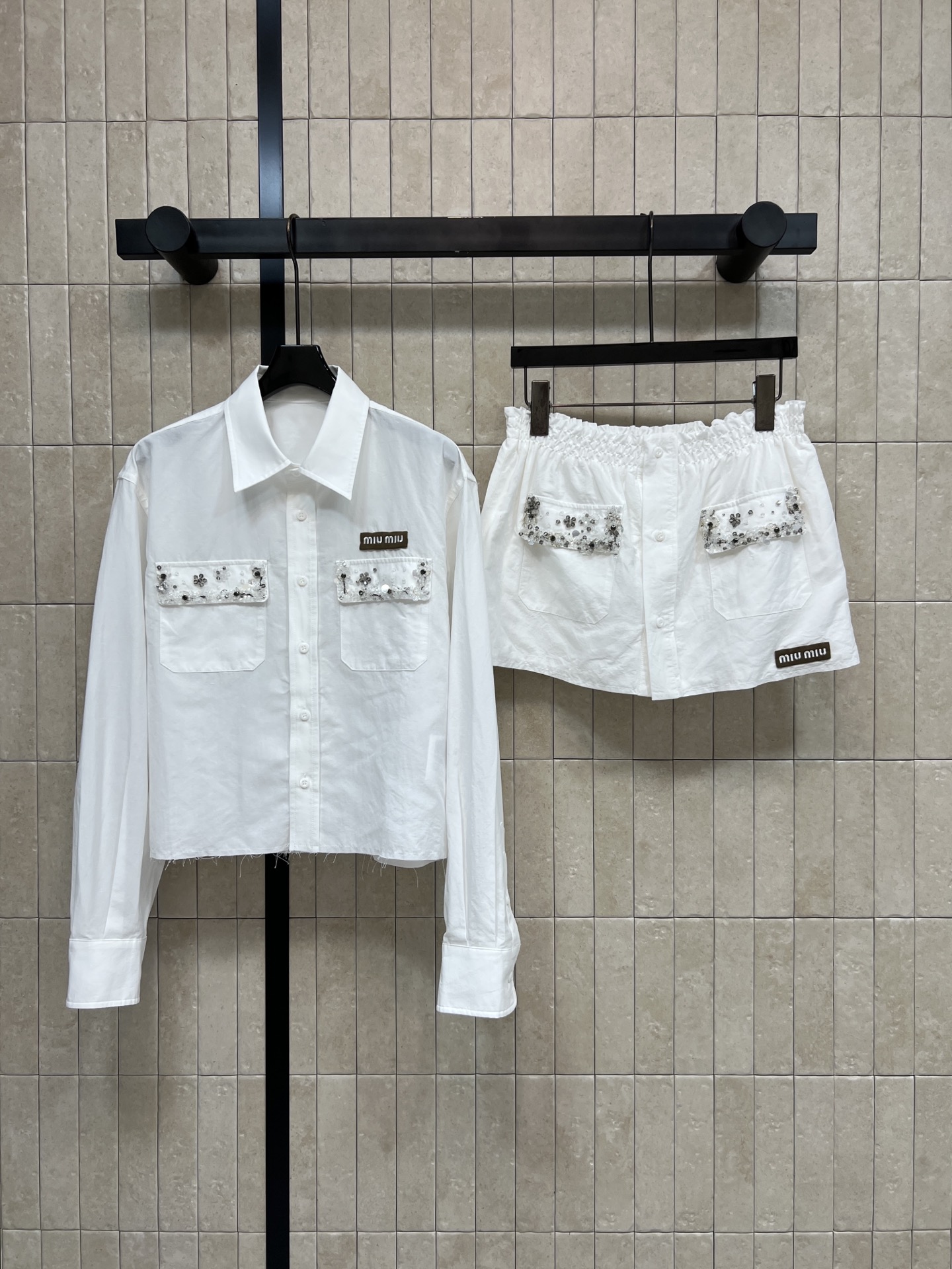 NO:933857,Shirt, short-sleeved MIU home 26 early autumn new style, white shirt suit, lapel long-sleeved shirt + short skirt, simple and clean, pockets embellished with handmade sequins and beads, exquisite and eye-catching logo, low-key logo, raw edge hem of the shirt with a casual atmosphere, elastic waist skirt does not flatter the figure, loose version hides the flesh and looks slimming, daily outing, shopping, refreshing and age-reducing, can be worn alone and matched with other items, it is also versatile and practical  One color and three sizes Size/S-M-L,,miumiu,skirts,shirts,T-shirt,19860909衬衣 短袖MIU家 26早秋新款 白色衬衫套装 翻领长袖衬衫+短裙 简约干净 口袋点缀手工亮片钉珠 精致亮眼 logo低调标识 衬衫毛边下摆自带随性氛围感 松紧腰短裙不挑身材 宽松版型藏肉显瘦 日常出游 逛街穿搭清爽减龄 单拆搭配其他单品也百搭实用 一色三码Size/S-M-L,,miumiu,skirts,shirts,T-shirt,,Women's clothing