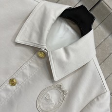 D家 26早秋新款 米白短袖衬衫 采用棉质混纺面料 扎实挺括 简约翻领设计 金色纽扣精致 胸口圆形刺绣logo徽章增添辨 D家 26早秋新款 米白短袖衬衫 采用棉质混纺面料 扎实挺括 简约翻领设计 金色纽扣精致 胸口圆形刺绣logo徽章增添辨