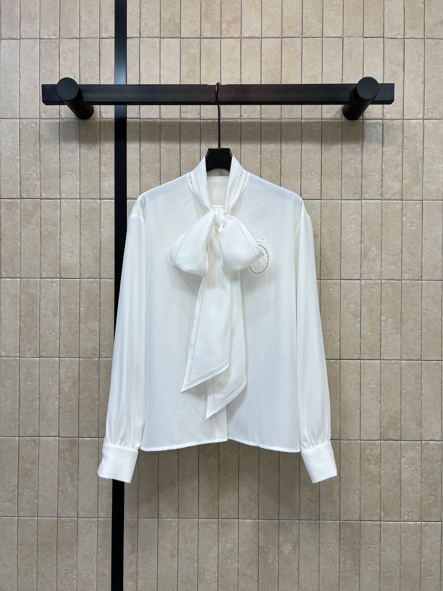 D家 26早秋新款 白色系带长袖衬衫 领口大飘带可自由折叠 衣身走线精致 氛围感直接拉满 胸前圆形logo徽章 垂顺面料