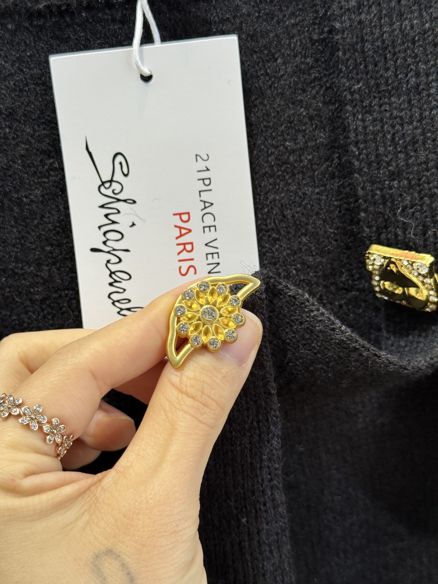 schiaparelli 侧纽扣设计的米白色针织衫短款版型，侧边采用斜排金属纽扣设计，兼具装饰性与实用性