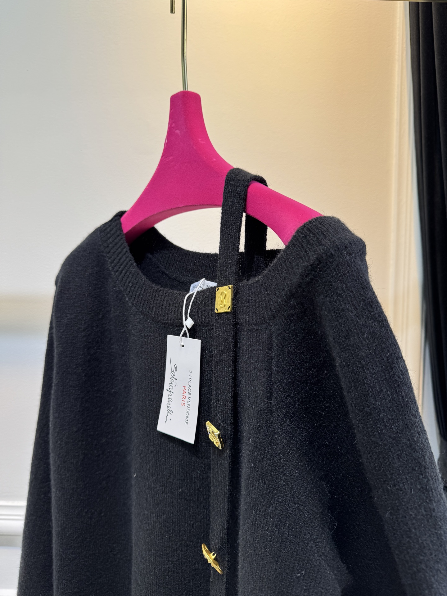 schiaparelli 侧纽扣设计的米白色针织衫短款版型，侧边采用斜排金属纽扣设计，兼具装饰性与实用性